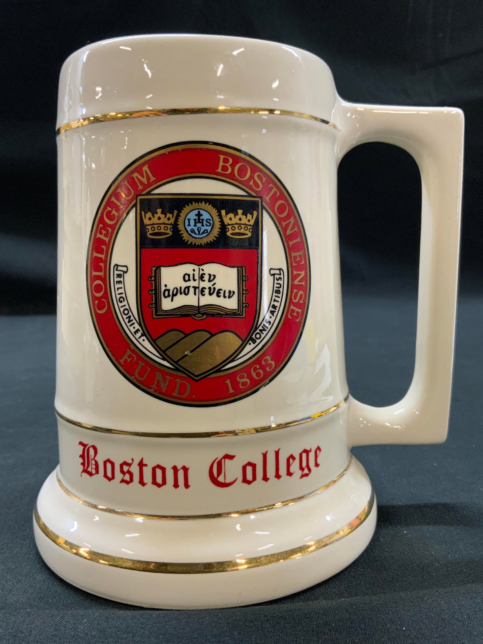 Vtg Boston College Ceramic Beer Stein Mug: Vintage Boston College Ceramic Beer Stein Mug. Circa 1980s. Styled in classic tankard silhouette. Body is finished in glossy cream glaze and accented by thin metallic gold gilded trim lines around
