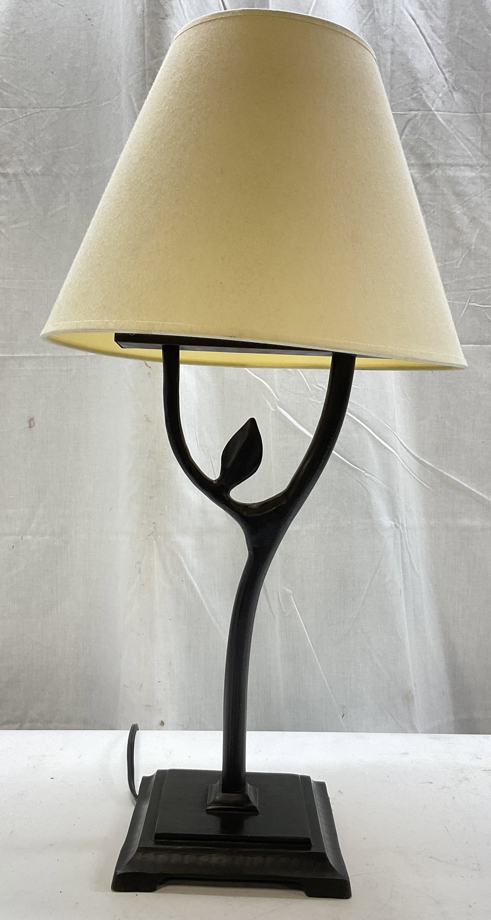 Vintage Black Metal Leaf Table Lamp W Shade: Vintage black metal leaf table lamp. Comes with white fabric shade. Painted black stem and base. Footed square base with stepped design. Ornate stem with leaf motif. Soft carved details. Measures
