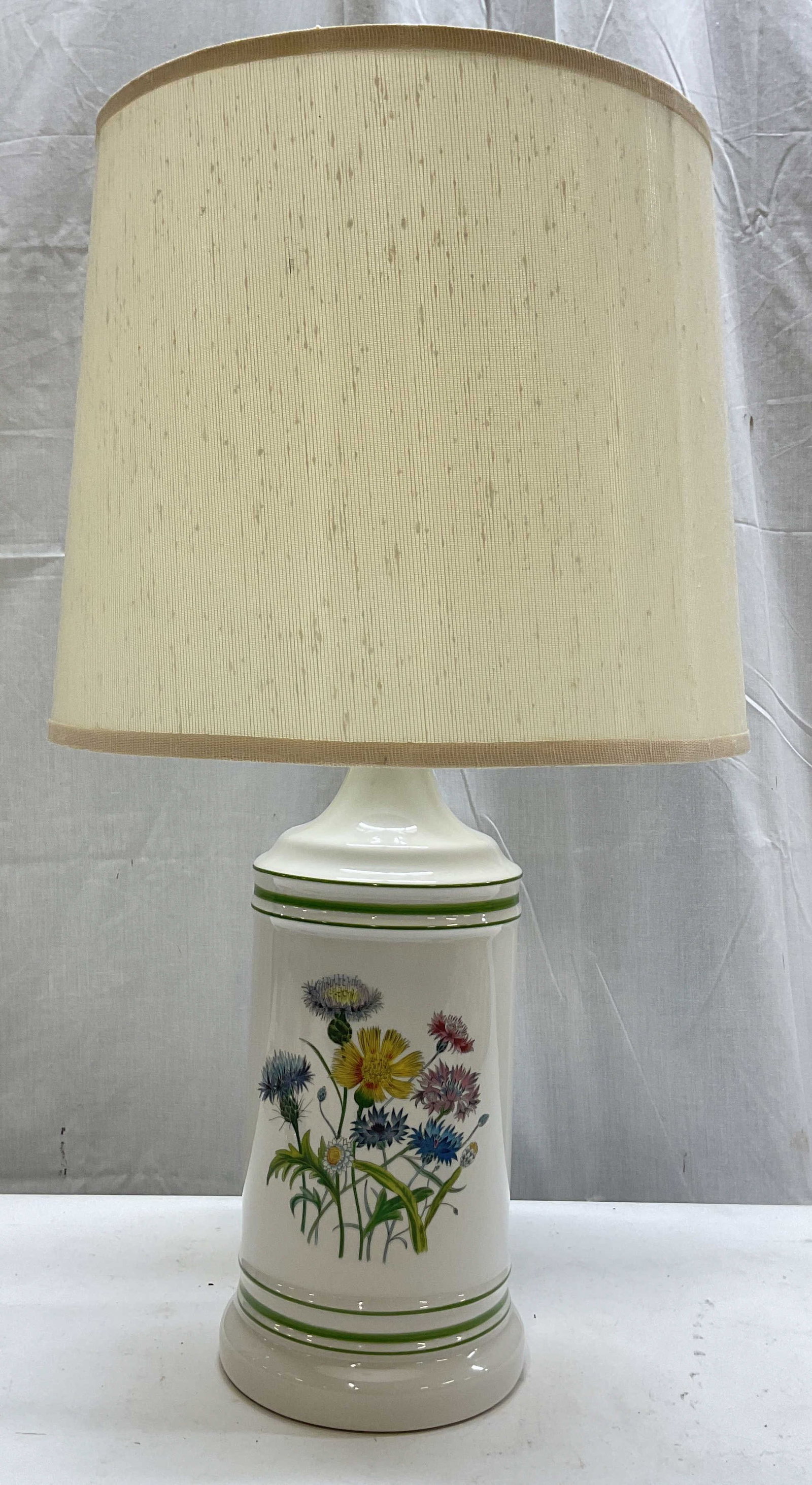 Vintage Botanical Porcelain Table Lamp W Shade: Vintage botanical porcelain table lamp. Comes with white fabric shade. Cylindrical base with varying colored floral motifs and double green stripe banding. Measures ht approx 23 inches diam approx 5.5