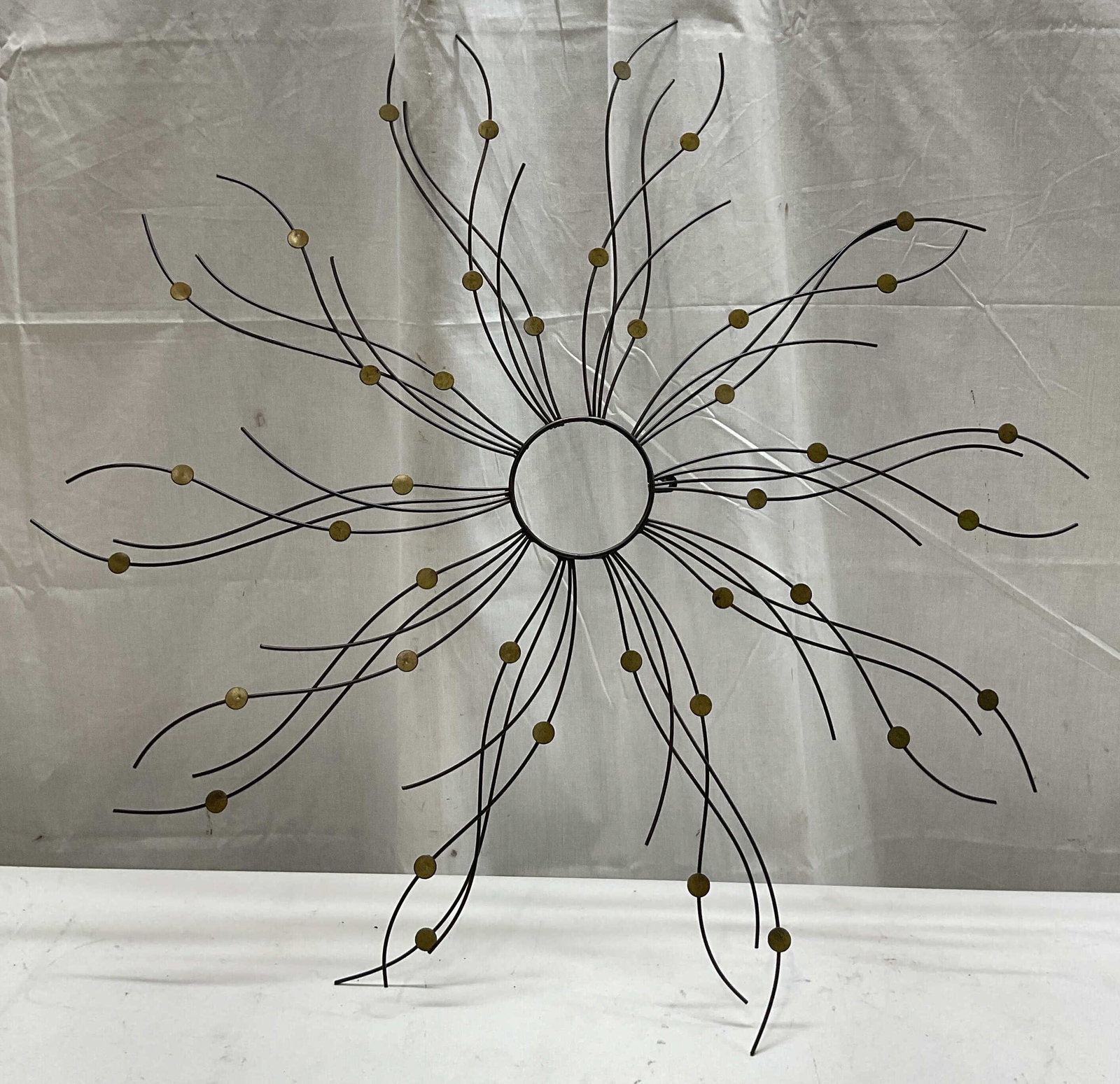 Contemporary Black Metal Sunburst Wall Decor: Contemporary black metal sunburst wall decor. Radiated curved stems. Accents with gold toned discs. Wavy design. Measures approx 29 x 30 inches. Surface wear consistent with exposure. Wall decor, wall