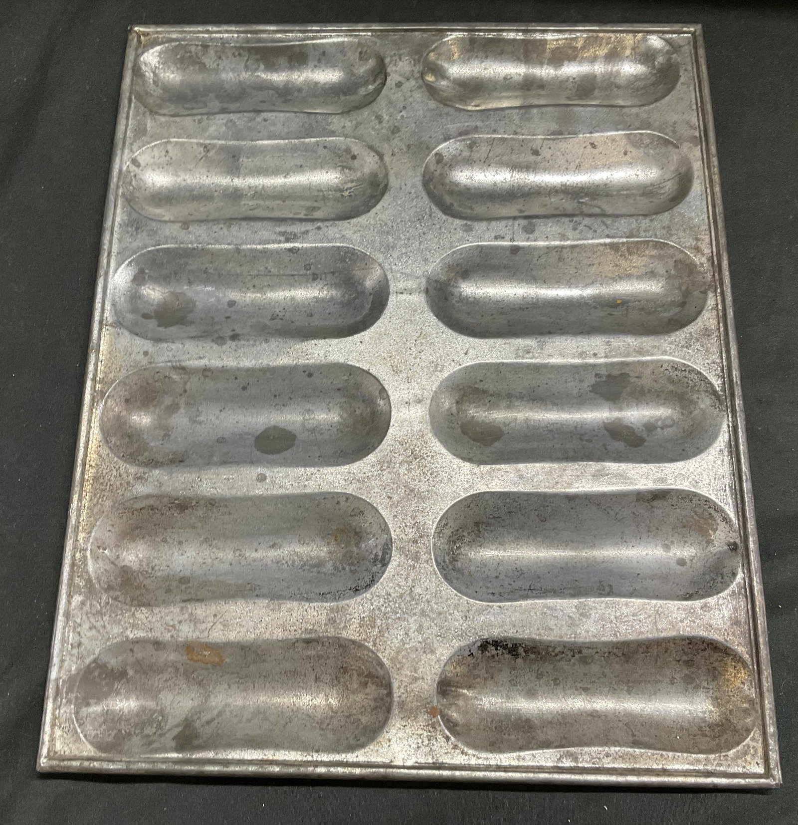 VTG 12-Cavity Tinplate Eclair Baking Pan: Vintage 12-Cavity Tinplate Eclair/Ladyfinger Baking Pan. Scratching and Tarnishing Present. Measures app 12in H x 9.5in W. Vintage Baking Pan, Tinplate, Eclairs, Lady Fingers, Kitchen Accessories 8 CS