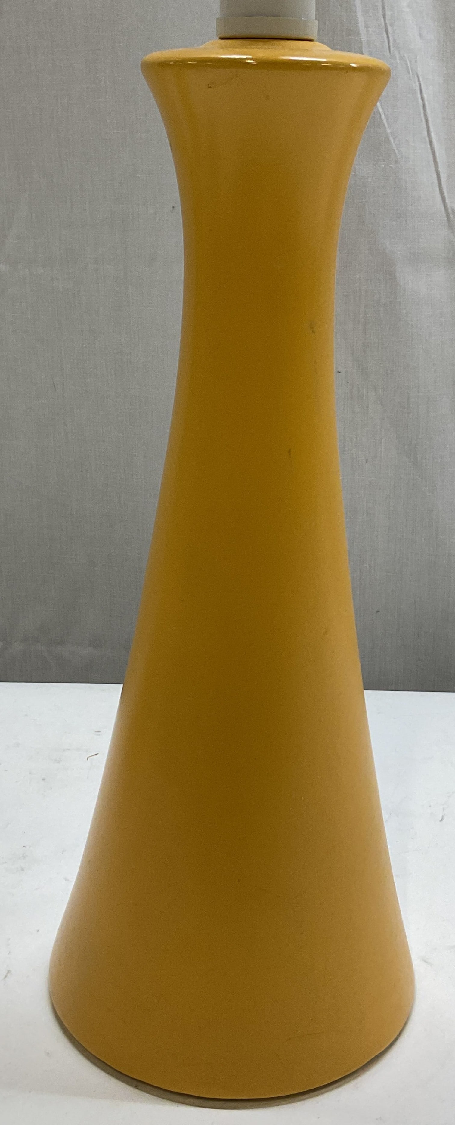 Vintage Yellow Ceramic Table Lamp: Vintage yellow ceramic table lamp. Hourglass shape, featuring a slender flared silhouette. Round base. Painted yellow. Measures ht approx 22 inches diam approx 5 inches. Not tested for function, sold