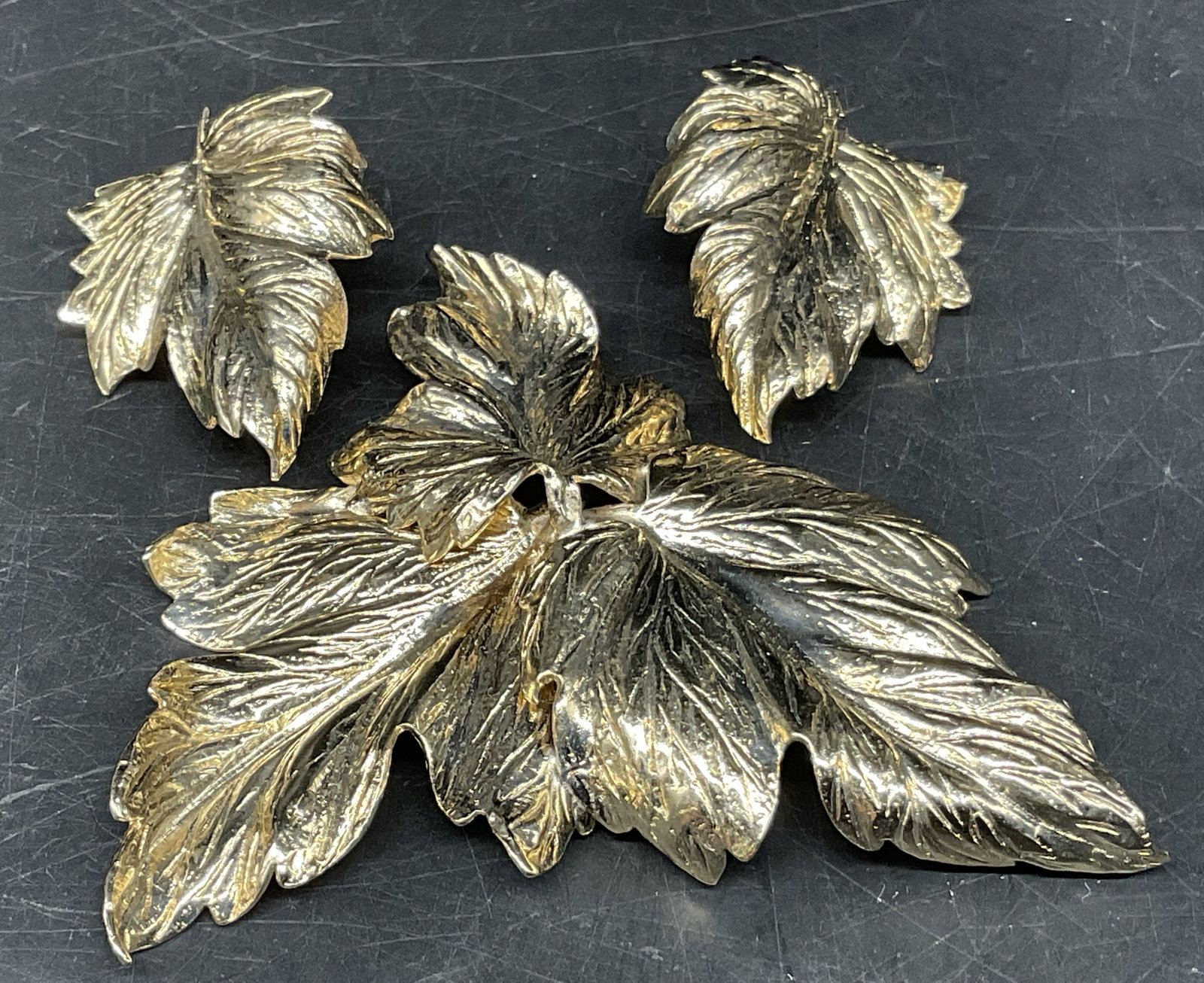 2PC VTG Bartek Gold-Toned Leaf Jewelry Set: 2 Pieces of Vintage Circa 1950s Bartek Gold-Toned Leaf Jewelry. Includes Overlapping 3 Leaf Design Brooch and 2 Single Leaf Design Clip-On Earrings. Textured 3D Realism Style with Detailed Raised Vein