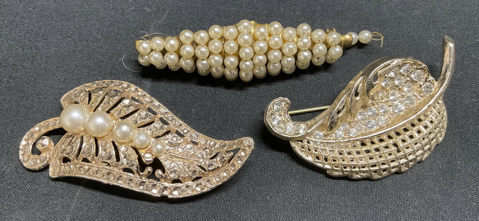 Lt3 Gold-Toned Jeweled Brooches: 3 Gold-Toned Jeweled Brooches. Leaf and Rhombus Shaped. Faux Pearl and Rhinestone Accents. Some Chipping in Metal. Largest Measures app 2.25in L x 1in W. Gold-Toned, Jeweled, Brooches, Leaf, Rhombus,