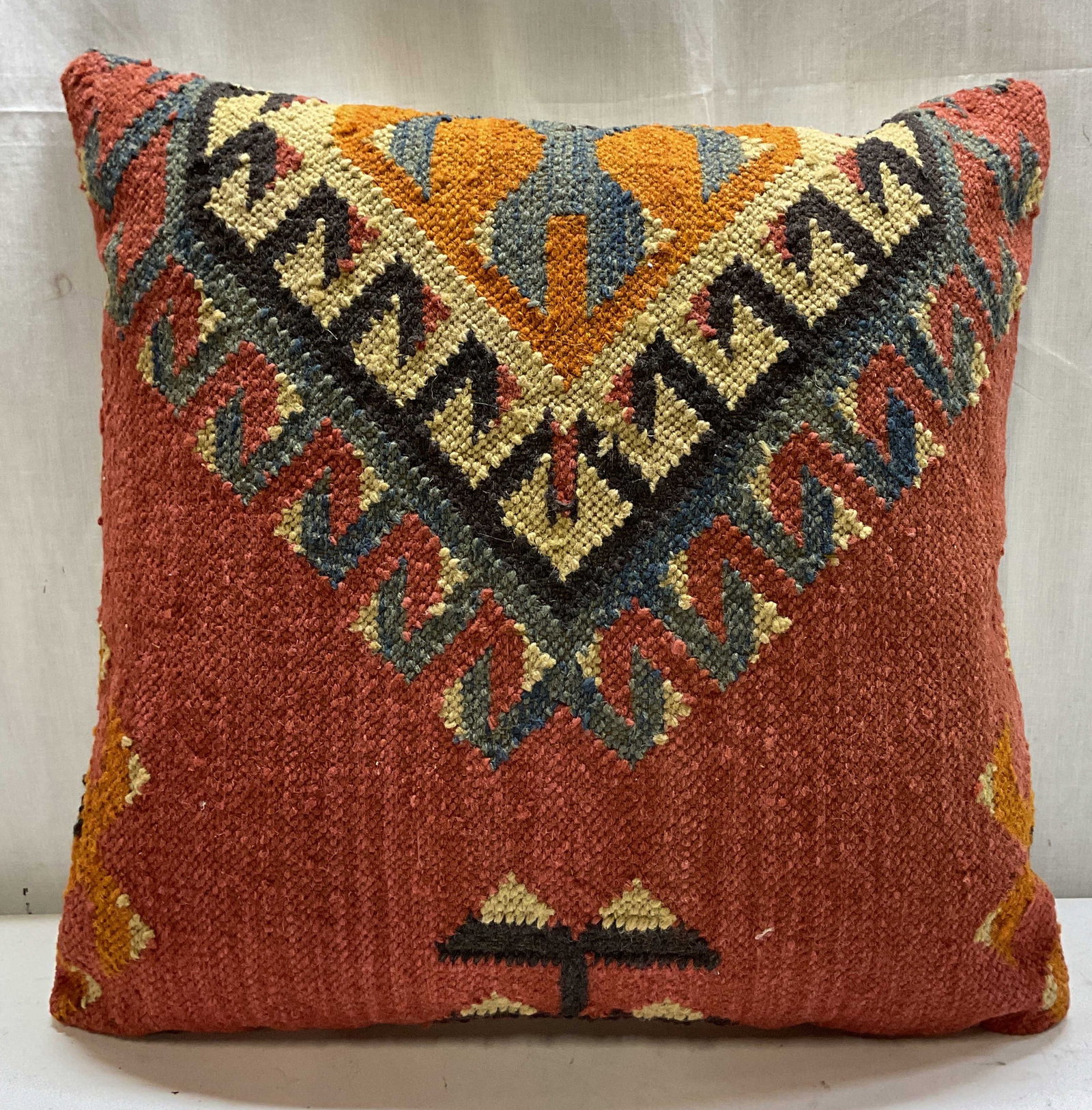 Vintage Turkish Wool Kilim Throw Pillow: Vintage Turkish wool Kilim throw pillow. Rustic terracotta background. Central geometric chevron medallion in orange, blue, and black tones. White back. Measures approx 20 x 21 inches. Surface wear co