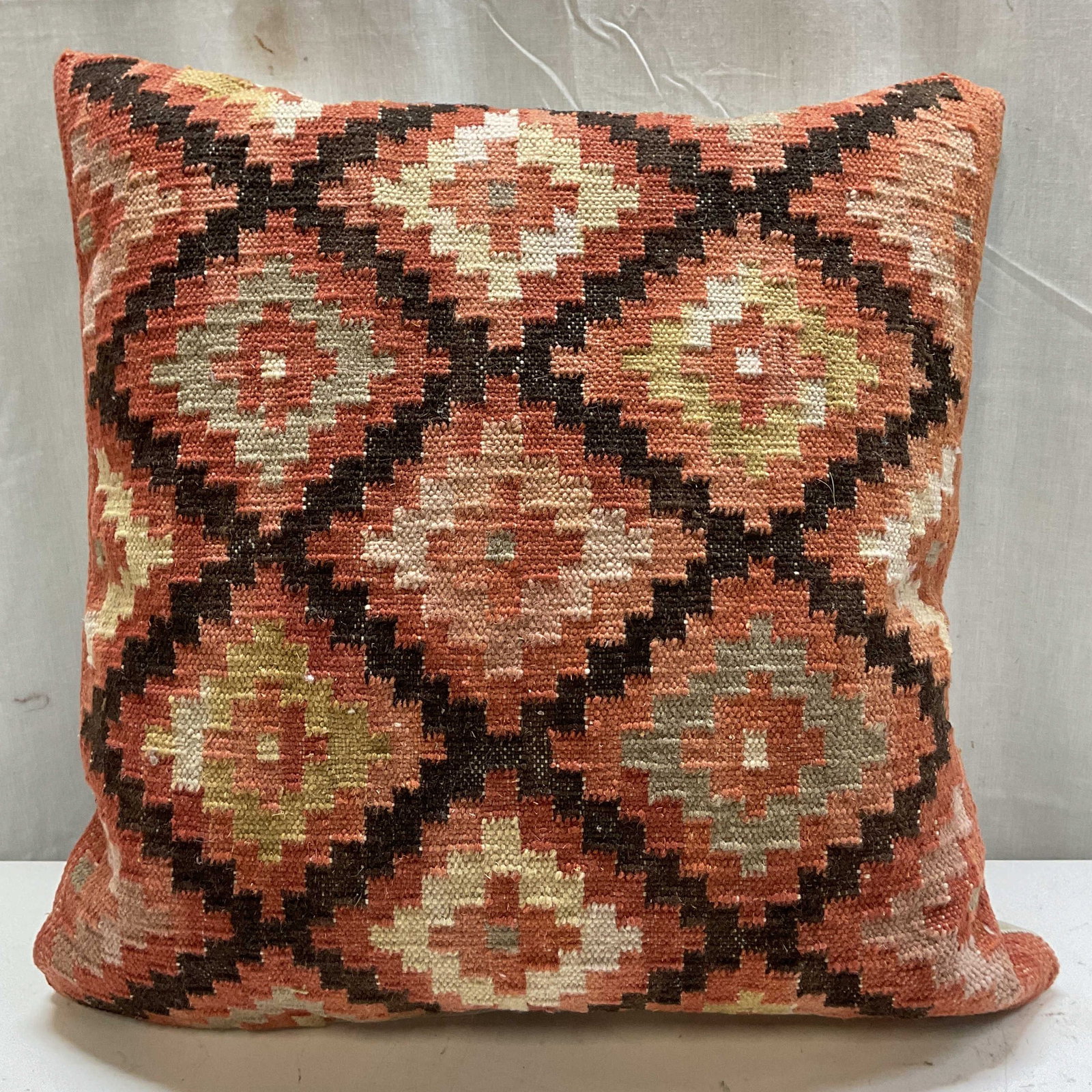 Vintage Turkish Wool Kilim Throw Pillow: Vintage Turkish wool Kilim throw pillow. Geometric diamond lattice pattern in warm terracotta, brown, and cream tones. White back. Measures approx 18 x 19 inches. Surface wear consistent with exposure