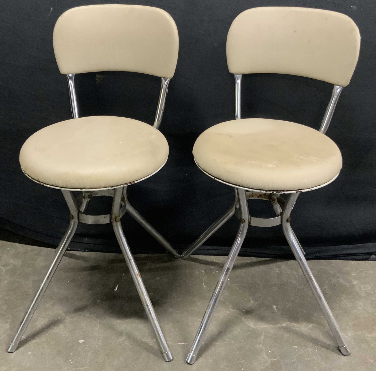 Pair COSCO Vintage Vinyl Upholstery Swivel Chairs: Vintage chrome & steel construction COSCO swivel chairs. Vinyl round seats. Splayed legs. Underside marked COSCO. Measures approx. 27.5Hx 12.25W x 13D in. Discoloration, surface wear, and losses to