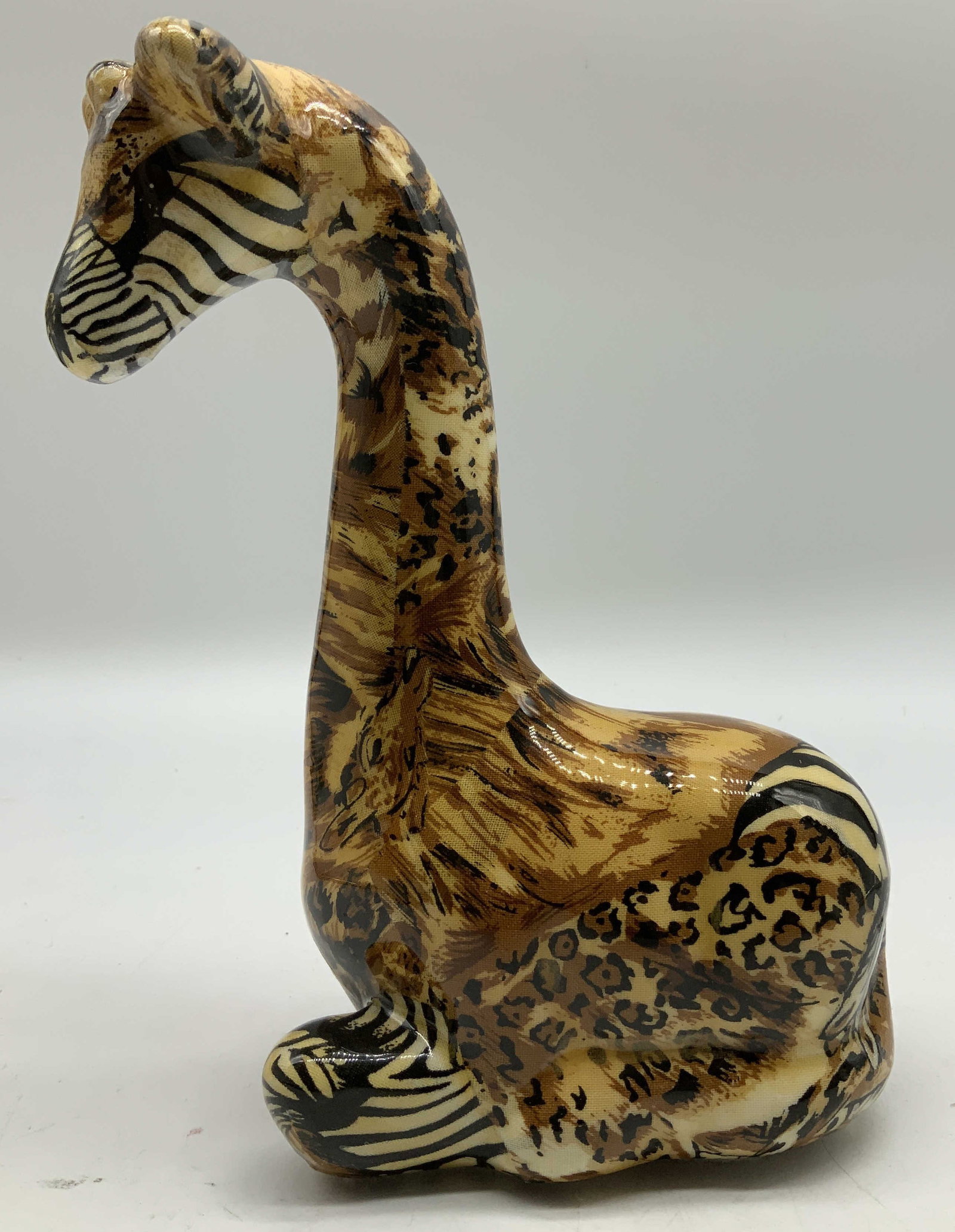 Vntg Seated Ceramic Giraffe Figurine: Vintage ceramic figurine depicting a seated giraffe with a decoupage design with various animal prints. Glossy finish. Surface wear consistent to age, use & exposure. Measurements: length 4.2in x