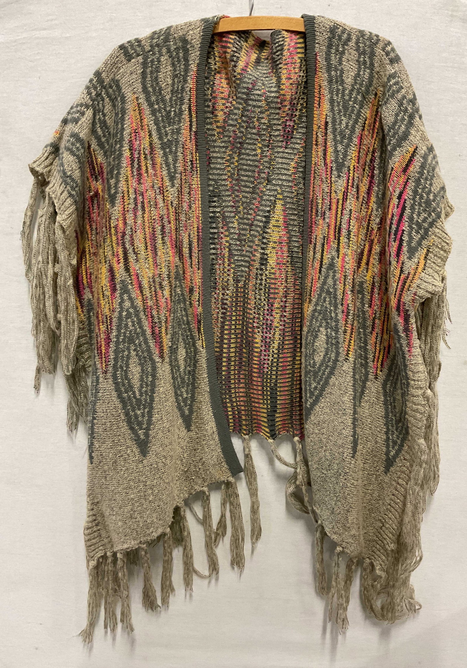 Vintage Wool Fringed Multicolor Shawl: Vintage wool fringed multicolor shawl. Feels like wool. Grey fringed trim. Button accents. Varying colors. Geometric pattern. Measures approx 32 inches across chest. Wear consistent with exposure.