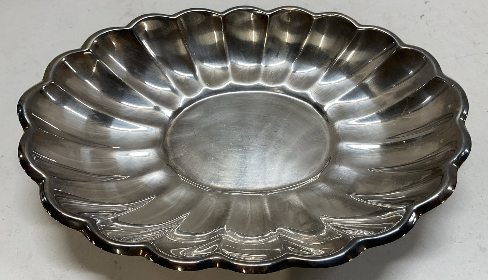 Reed & Barton Holiday Silver Plated Serving Dish: Reed & Barton Holiday silver plated serving dish. Marked Reed & Barton on underside. Holiday pattern. Oval shaped dish. Scalloped edge. Ribbed surface. Measures approx 10.5 inches in diameter.