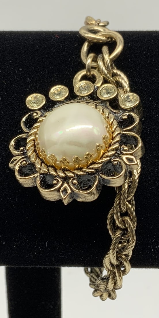 Vtg Gold Tone Faux Pearl Slide Bracelet: Vintage gold tone slide bracelet with focal charm. Circular charm houses smooth cream colored dome faux pearl cabochon centered in rope twist border. Linked to double interlocking rope chain with spri