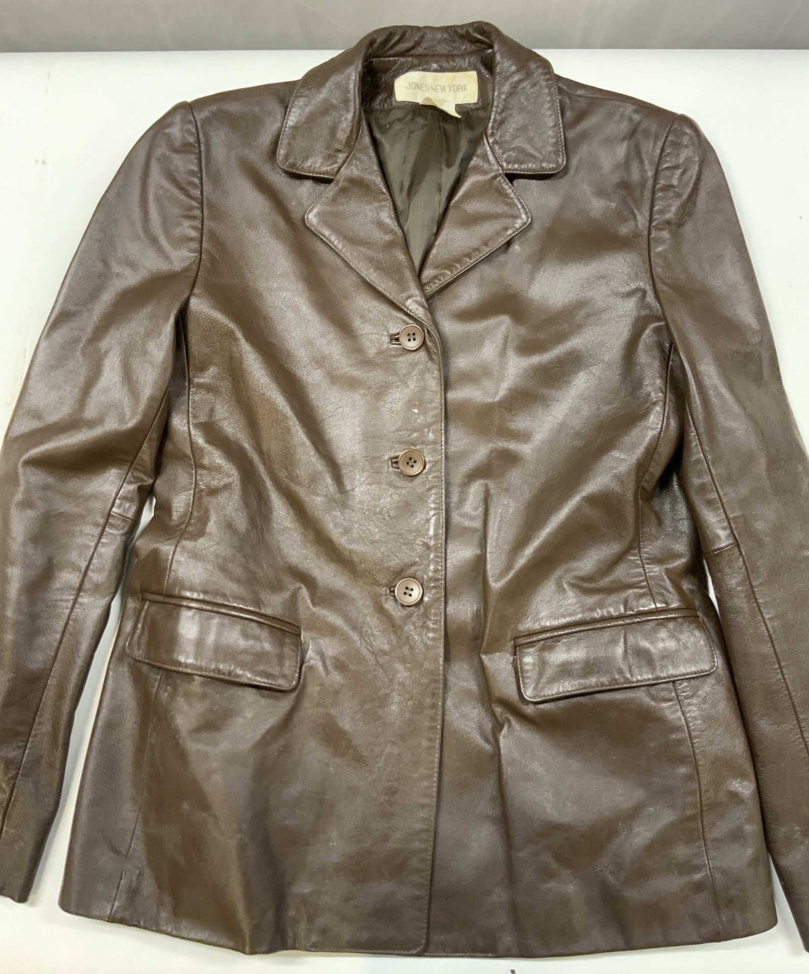 Vntg Jones New York brown leather blazer 1990s: Vintage Jones New York brown leather blazer. Made from 100% leather in the 1990s. Size 6. This tailored three button style was a quintessential corporate to casual piece for their late 1990s
