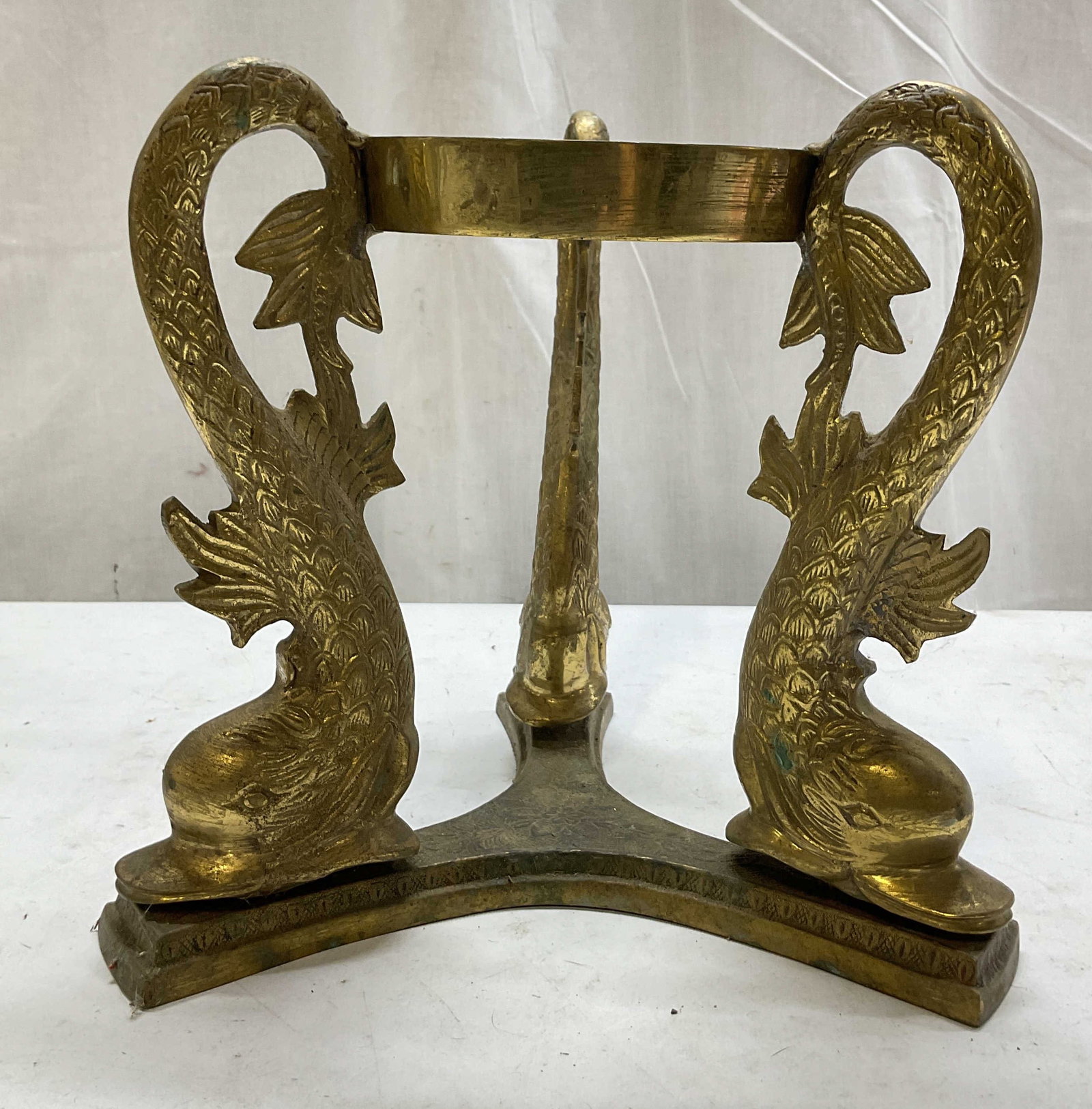 Vtg Brass Dolphin Three Legged Decorative Stand: Vintage brass dolphin three legged decorative stand. Round top. Three legged base. Sculpted stylized dolphin motifs. These form the legs and curve upwards as support. Detailed features and textures. E