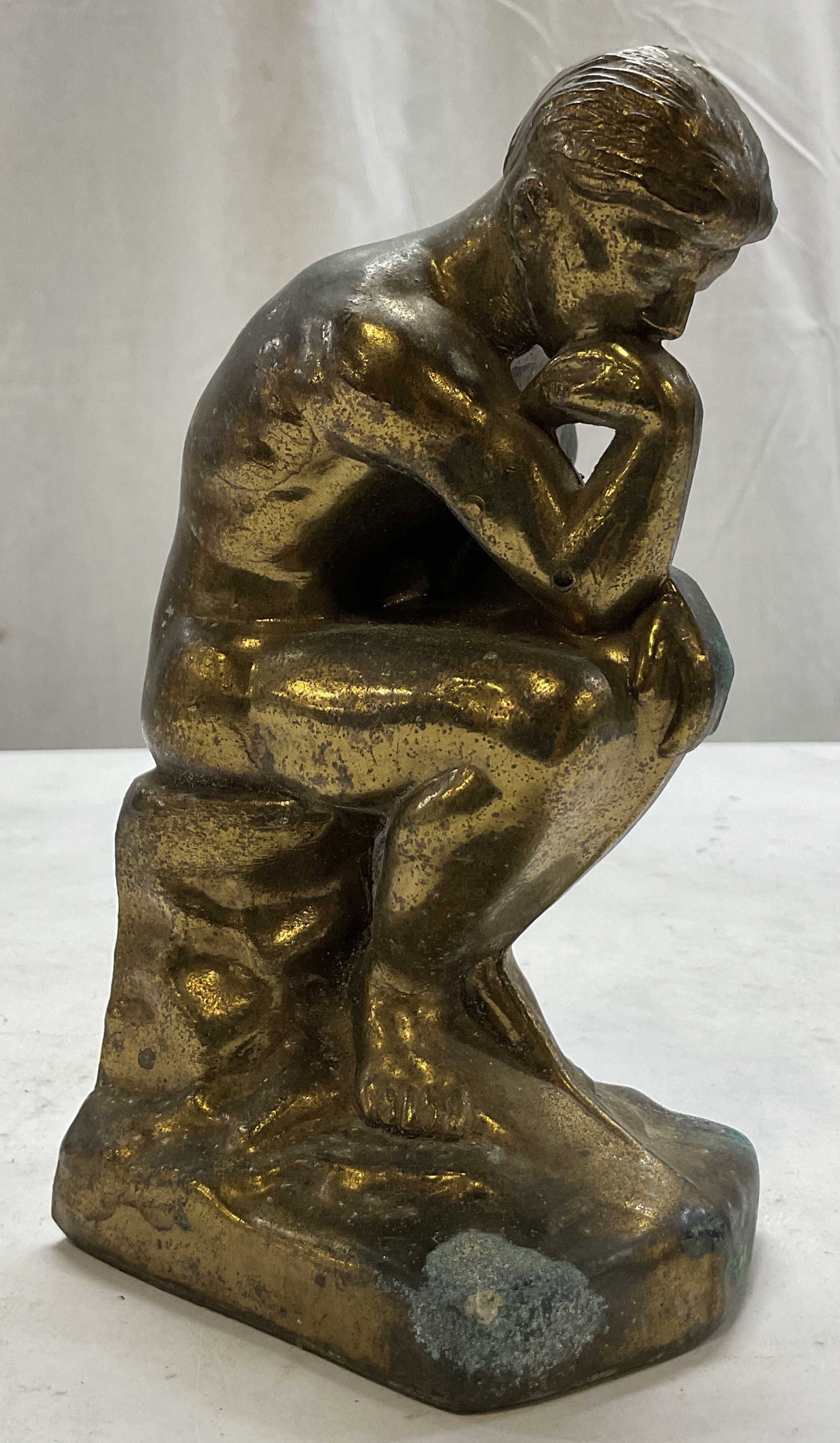 Vintage 1928 Cast Metal The Thinker Bookend: Vintage 1928 cast metal The Thinker bookend. Brass finish. Sitting male figure, hunched over with his hand resting on his chin. Detailed features. Measures approx 3 x 3.5 x 6.5 inches. Scratching,