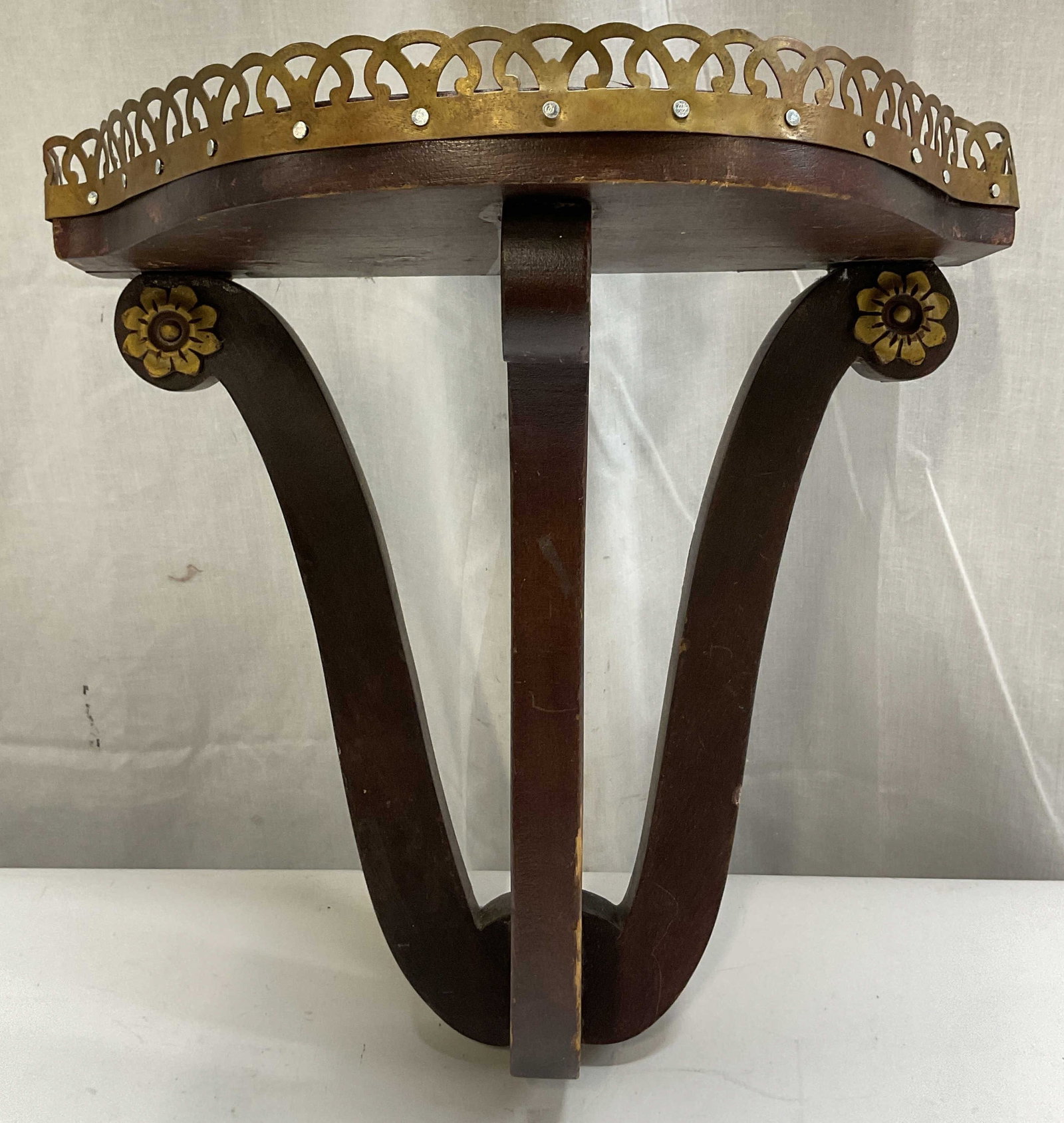 Vintage Wooden & Brass Toned Wall Shelf: Vintage wooden and brass toned wall shelf. Brass toned floral motifs and decorative pierced gallery rim, scalloped edge. Semi circular top. Scrolled support brackets. Wall hooks for mounting. Measures