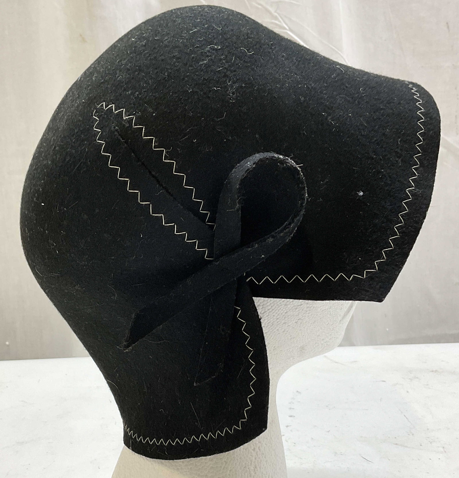 Helen Welsh Black Wool Cloche Hat Italy W Box: Helen Welsh black wool cloche hat. Made in Italy. 100% wool. White zig zag stitching. Side bow accent. Fitted bell shaped wear. Comes in storage box. Measures approx 9.5 inches in diameter. Surface we