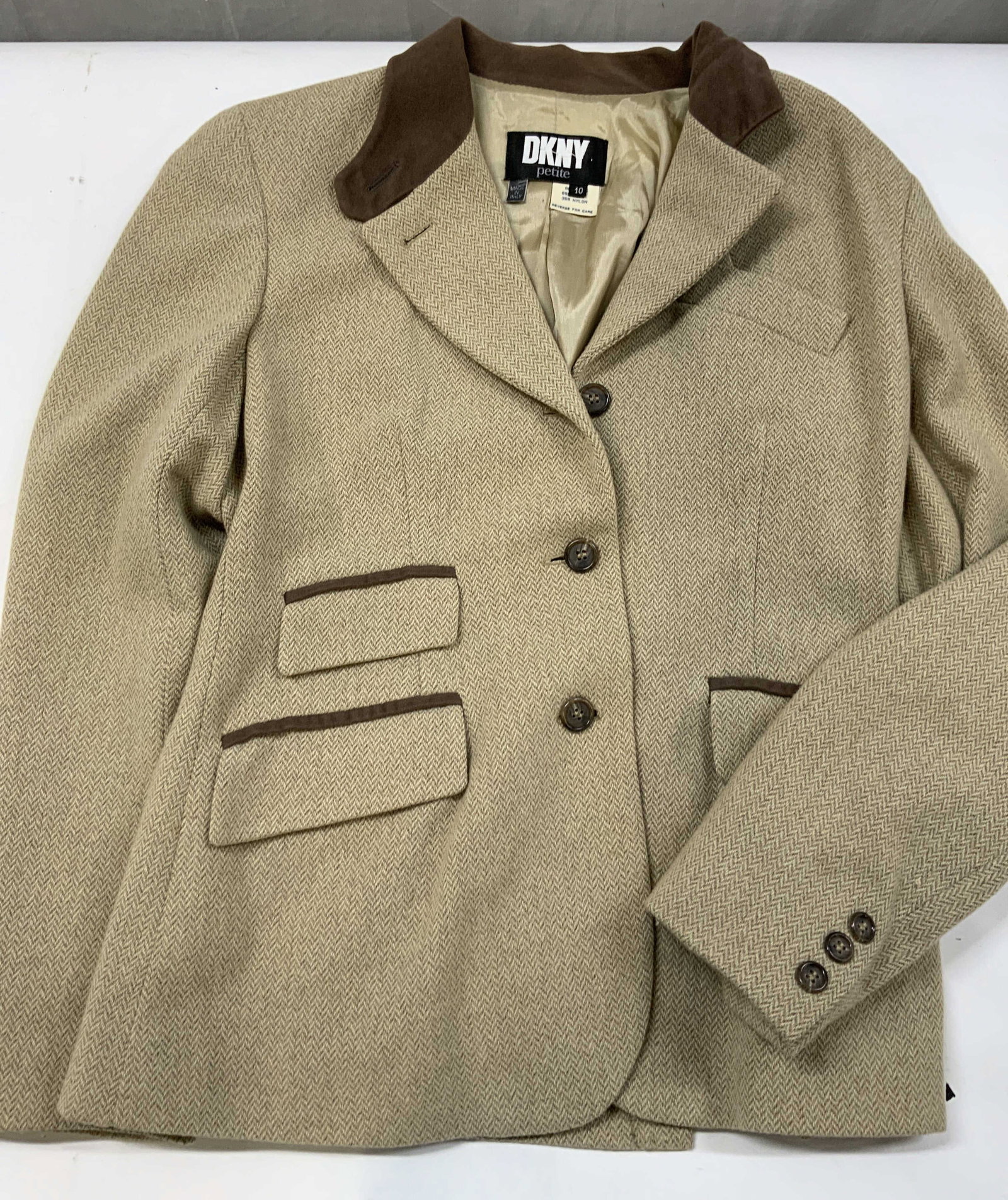 Vntg DKNY tan herringbone blazer , Italy: Vintage DKNY tan herringbone blazer. Made in Italy form a wool nylon blend. Size 10 petite. Blazer features a tan herringbone pattern with brown trim on the collar and pockets. 2 front flap pockets in