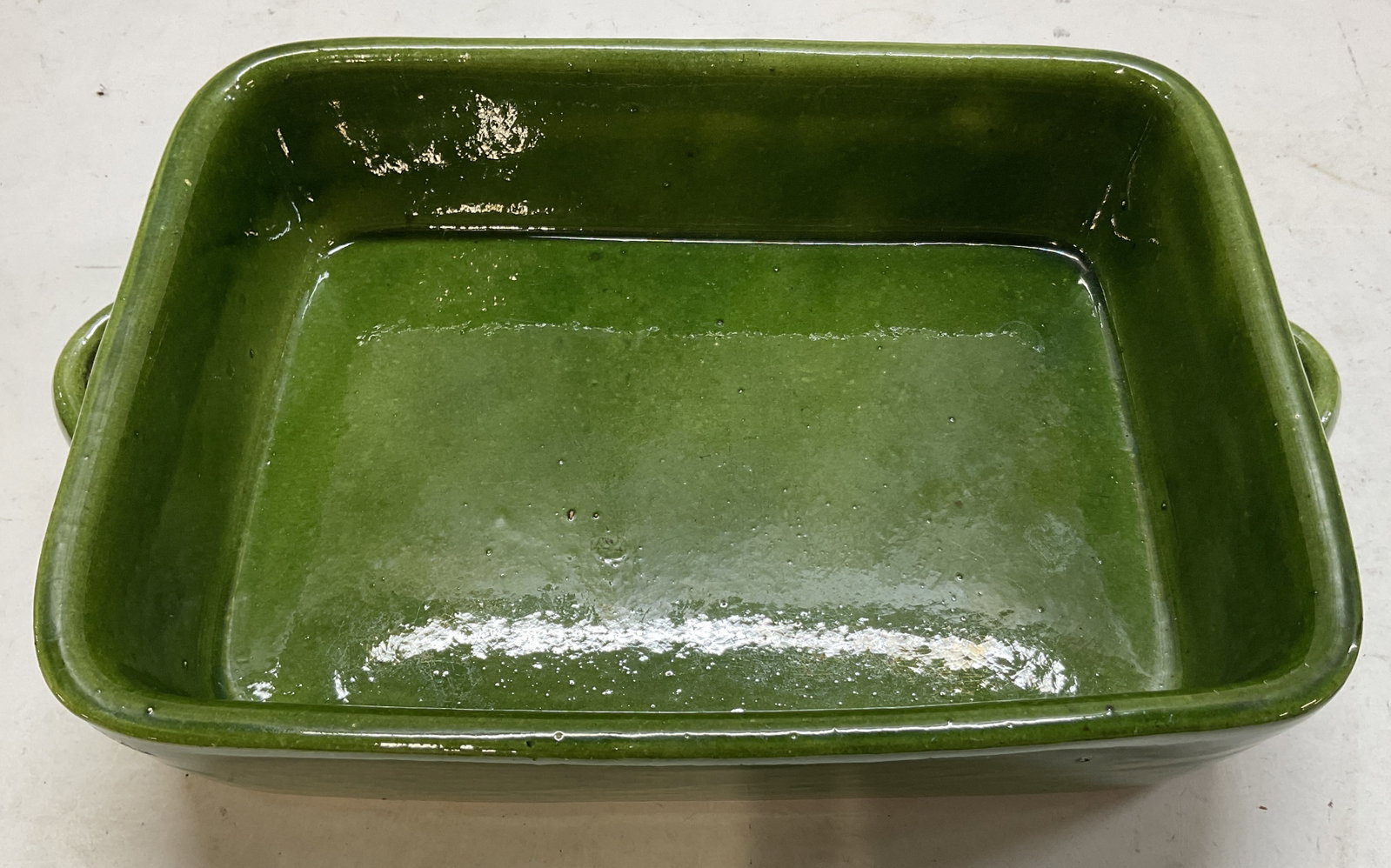 Vintage Green Glazed Ceramic Baking Pan: Vintage green glazed ceramic baking pan. Rectangular shape, handles in either side. Glossy finish. Underside is unglazed. Measures approx 8 x 10.5 x 2.5 inches. Crazing. Baking pan, pan, kitchenware,