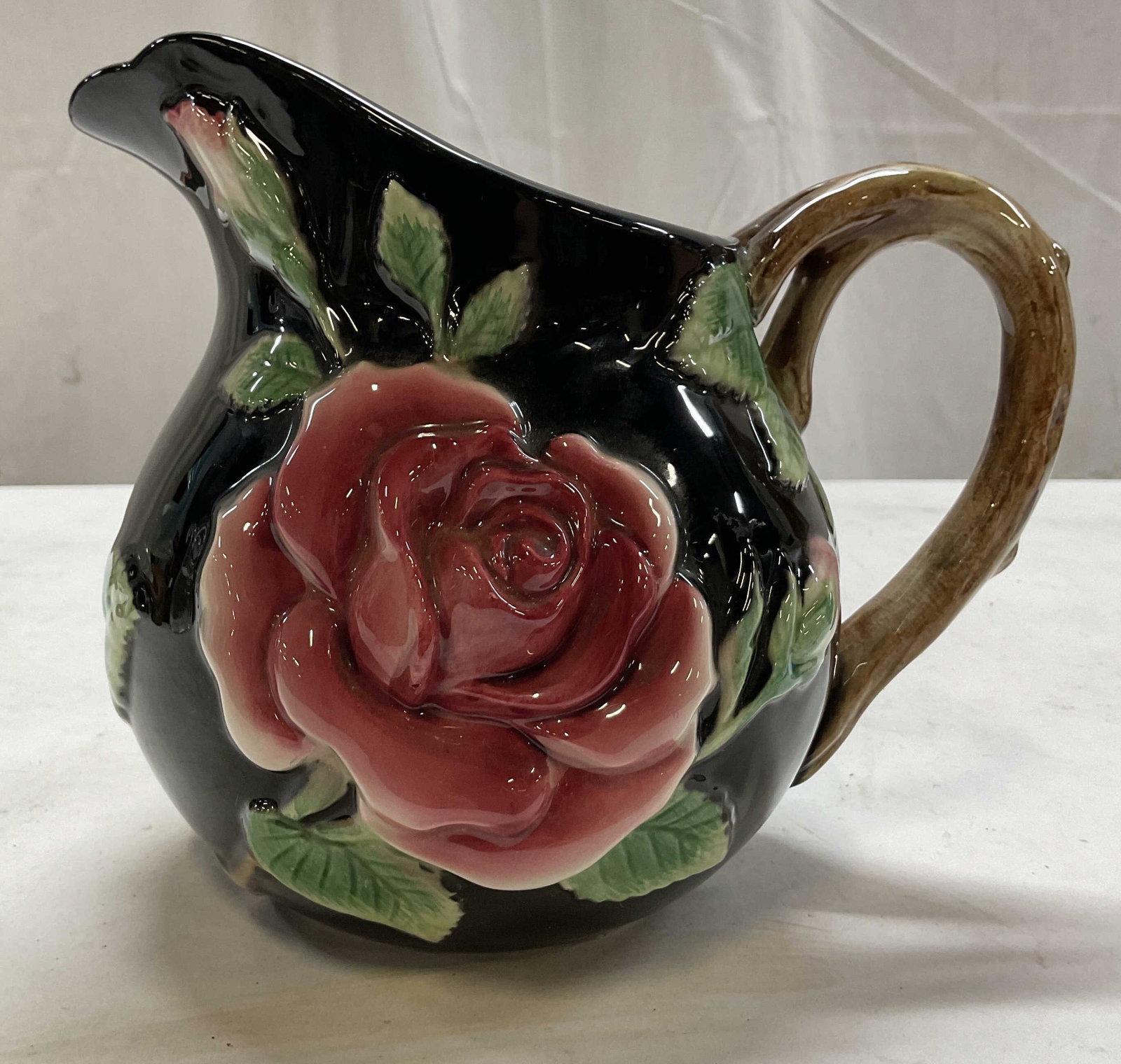 1987 Fitz & Floyd Midnight Rose Pitcher Japan: Fitz & Floyd Midnight Rose ceramic pitcher. Marked on underside, reads FF 1987 1.5 quarts Japan. Glossy finish, black glazed. Brown branch style handle. Curved spout. Embossed floral rose motifs in