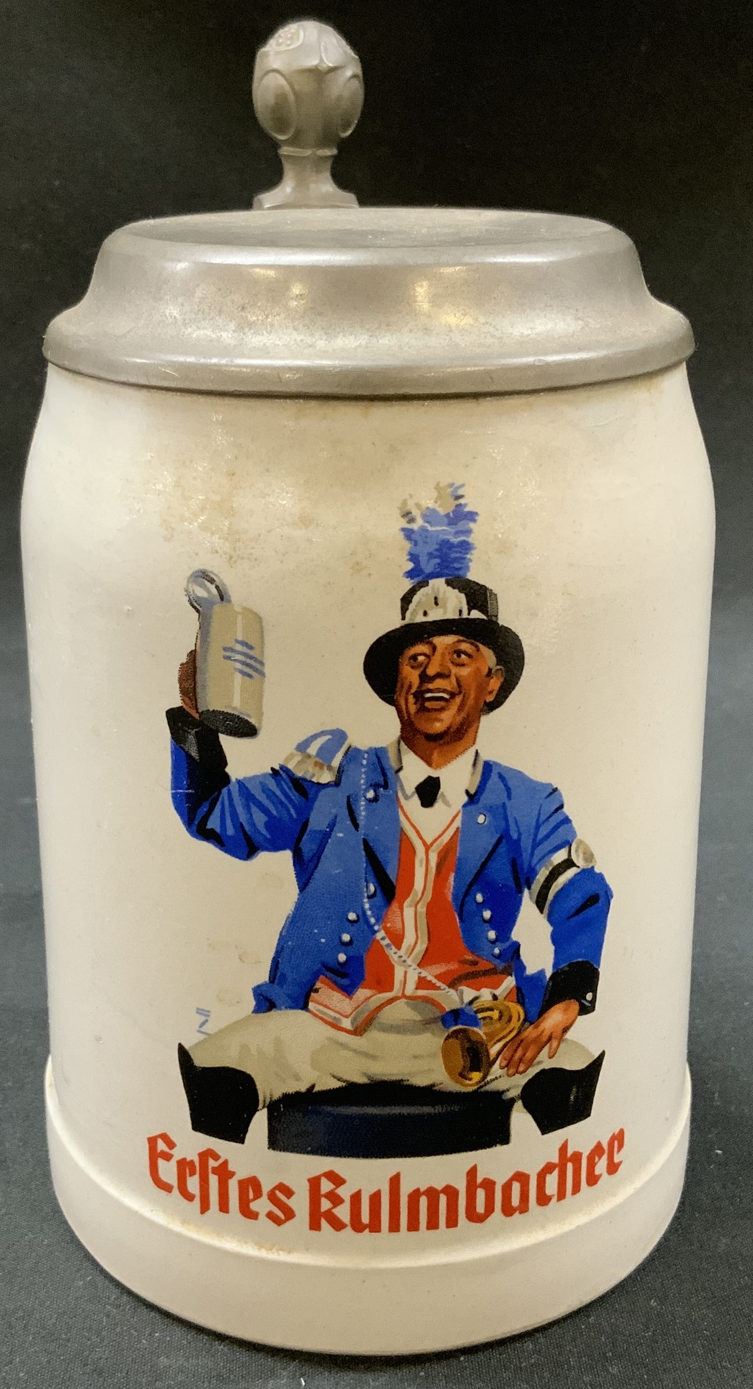 Vtg Erstes Kulmbacher Beer Stein, Germany: Vintage Erstes Kulmbacher brewery Beer Stein. German ceramic stoneware body with multicolor graphic depicting man in traditional Bavarian festival attire. Fitted with hinged pewter lid with