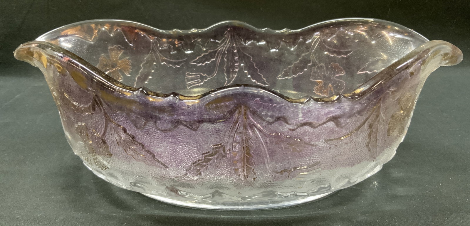 Vtg Purple Iridescent Pressed Glass Bowl: Vintage Oval pressed glass bowl designed with double pointed ruffled rim. Purple and marigold iridescent coating along upper edges and exterior body. Exterior walls molded with embossed pattern of