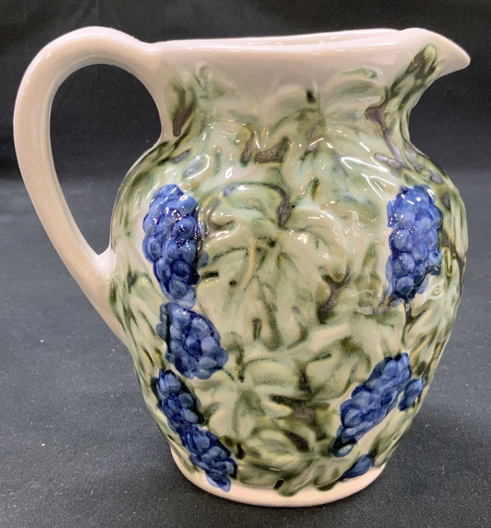 Vtg John B Taylor Ceramics Grape Pitcher: Vintage mid century John B Taylor Grape pitcher. Glazed pottery produced in Louisville, Kentucky. Features molded relief of green grape leaves and blue purple grapes. Flared pouring spout, ear shapes