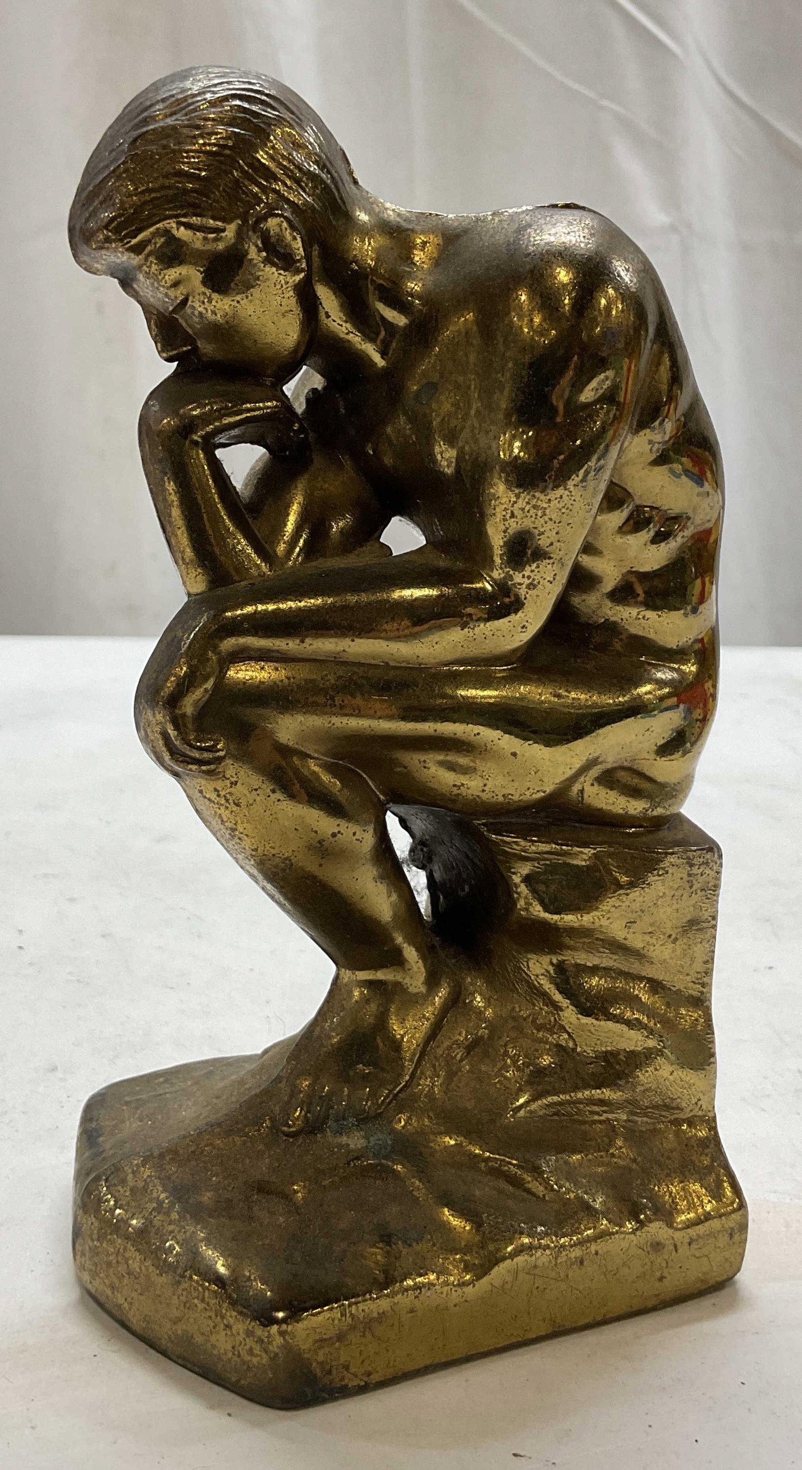 Vintage 1928 Cast Metal The Thinker Bookend: Vintage 1928 cast metal The Thinker bookend. Brass finish. Sitting male figure, hunched over with his hand resting on his chin. Detailed features. Measures approx 3 x 3.5 x 6.5 inches. Scratching,