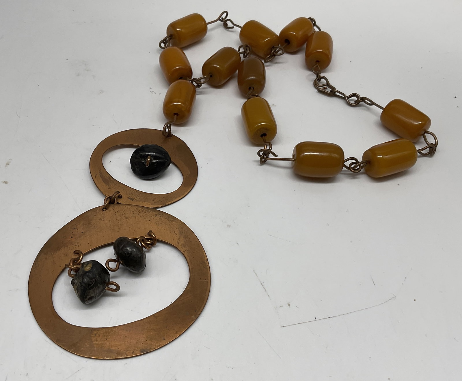 Mid-Century Modernist Statement Necklace: Mid-Century Modernist Circa 1950s-1970s Statement Necklace. Bi-Level asymmetrical copper drop consisting of two flat, open hoop links. Tumbled stone accents. Barrel-Shaped butterscotch colored bakelit