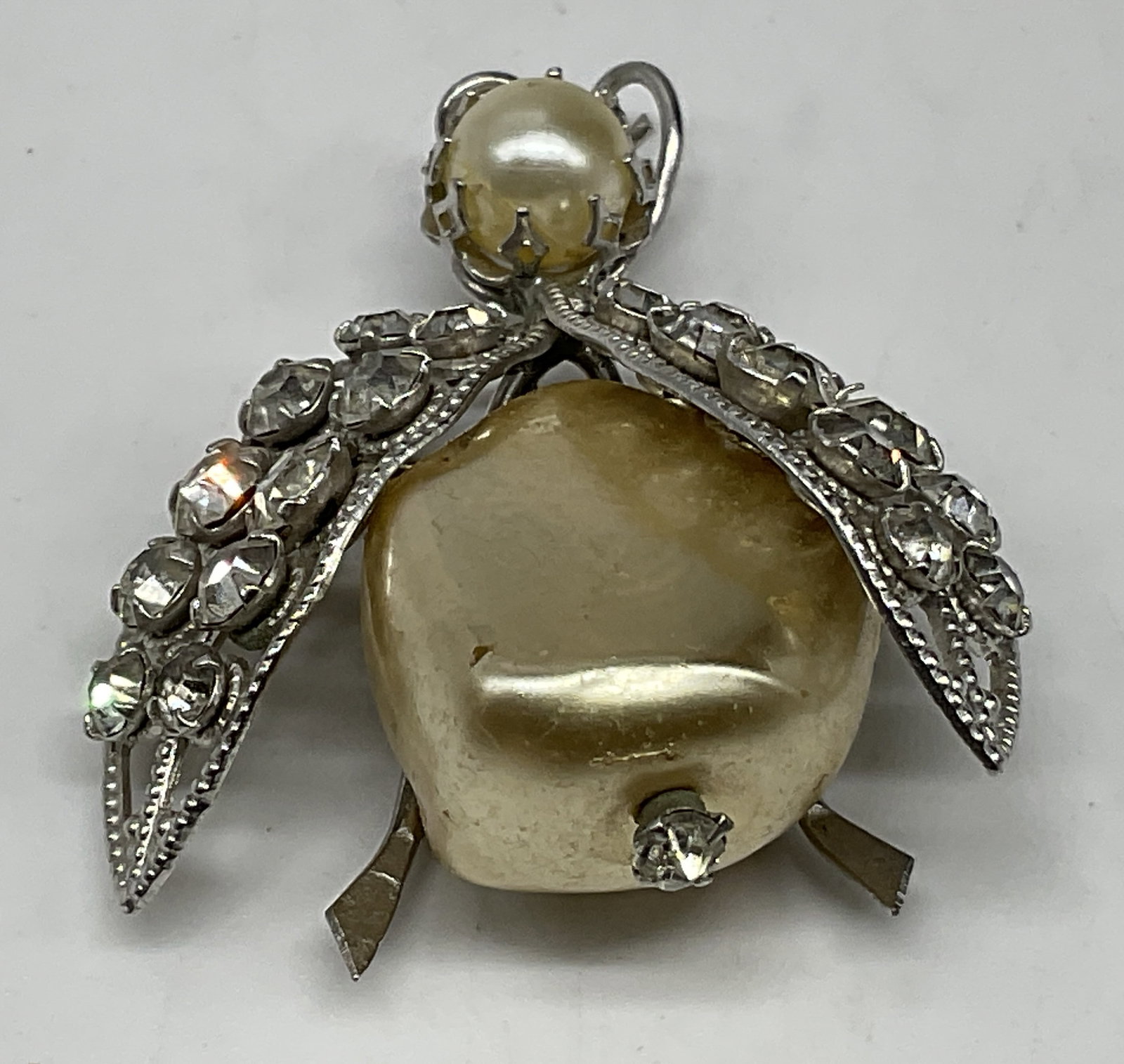 VTG Jelly Belly Style Ladybug Brooch: Vintage Circa 1950s-1960s Jelly Belly Style Ladybug Brooch. Silver-toned filigree. Cream-colored glass bulbous body. Faux pearl head. clear rhinestone accents. Chipping to finish and oxidization