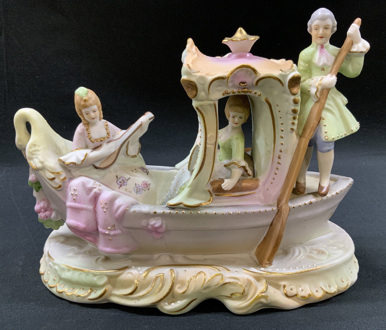 Vtg German Style Porcelain Venetian Gondola Fig.: Vintage German Style Hand painted porcelain Venetian gondola scene with three firgures in 18th century attire. Woman playing lute, woman holding fan, and oarsman. On molded scalloped base with gold gi