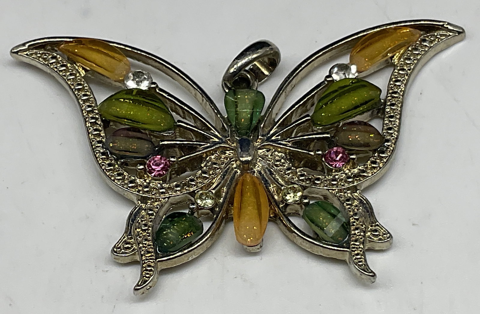 VINTAGE Open-Work Butterfly Pendant: Vintage Open-Work Butterfly Pendant. Silver-Toned with yellow, green, and smoky grey glass stones. Pink rhinestones. Condition consistent with age and exposure. Measures approx 1.5in H x 2 in L.