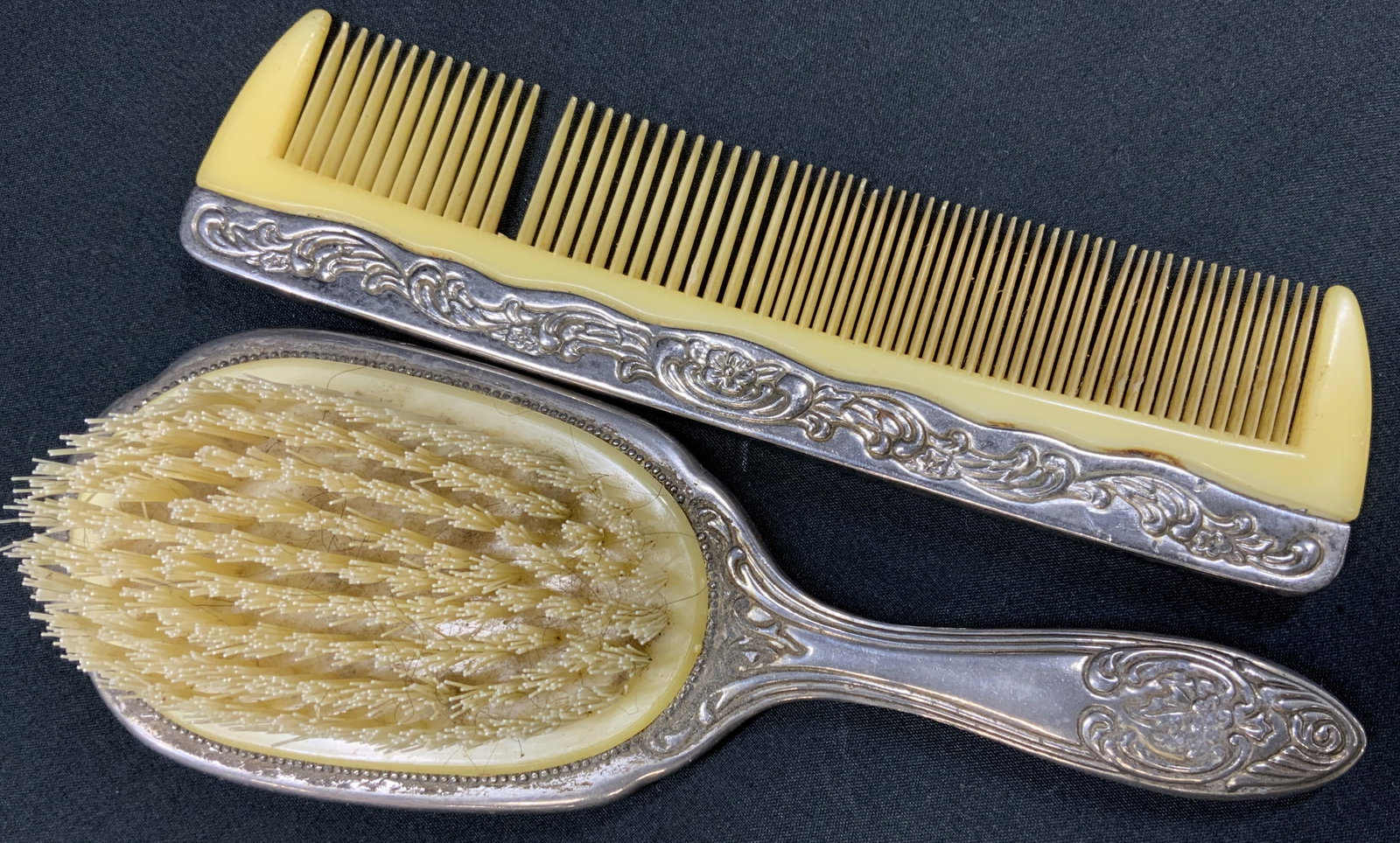 Vtg Repousse Vanity Hairbrush and Comb Set: Vintage vanity dresser hairbrush and comb set features ornate repousse border decorated with embossed scrollwork, foliate patterns, and central un engraved cartouche panel. Brush bed dense with nylon 