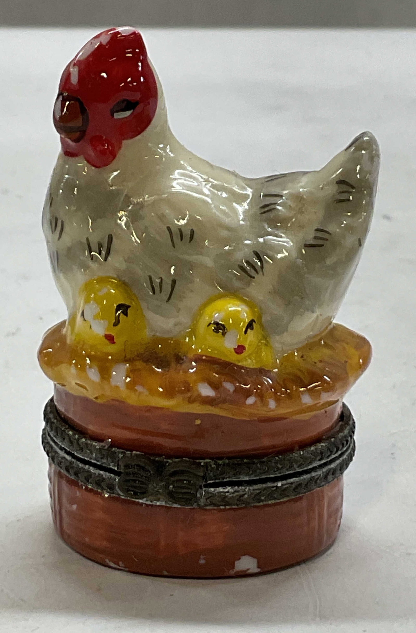 Vintage Porcelain Hen & Chicks Trinket Box: Vintage porcelain hen and chicks hinged trinket box. Round box with ribbed surface. Hen and chicks motifs on lid. Hinged lid with decorative bow closure. Hand painted in varying colors and details. Me