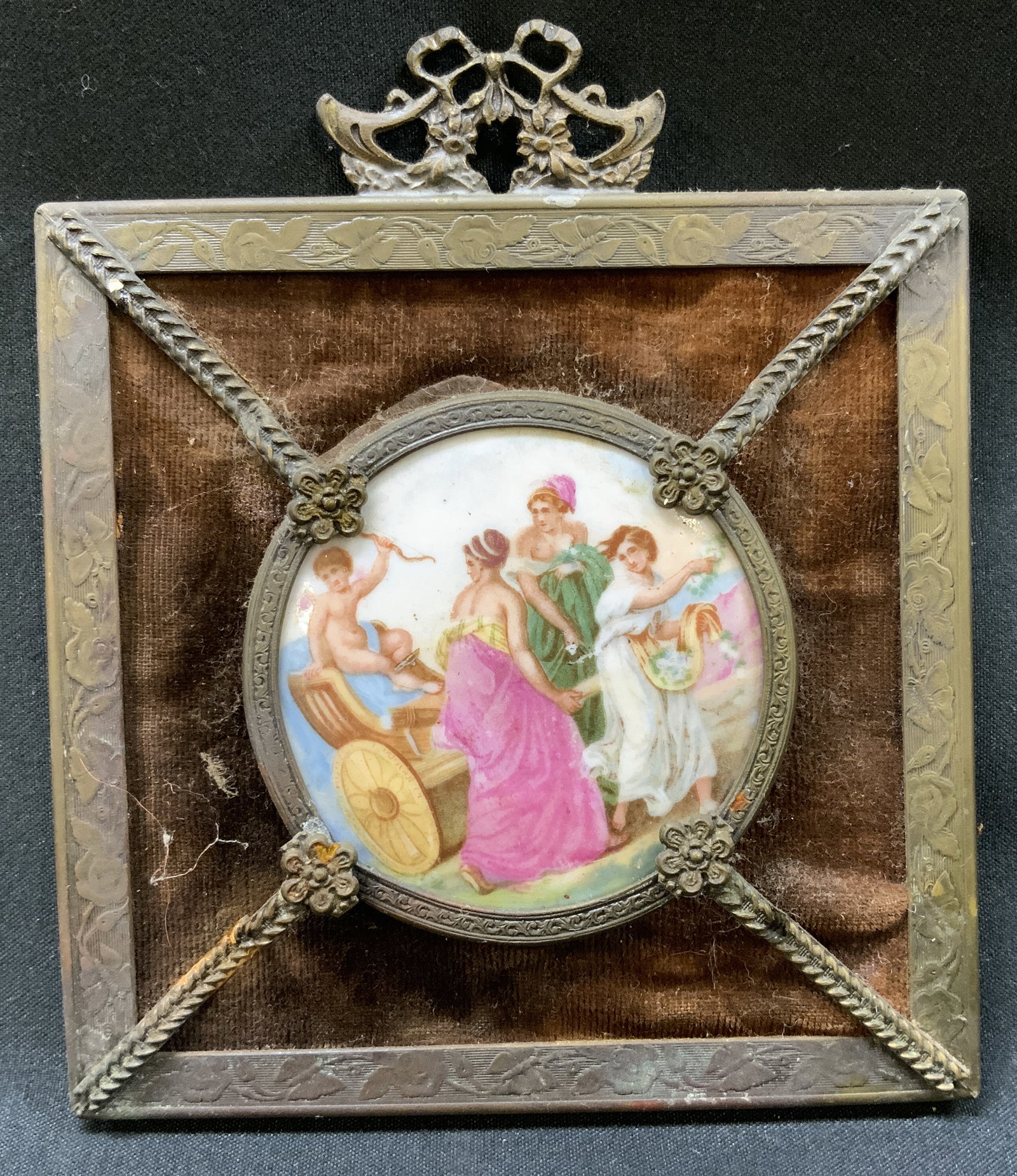 Vtg Velvet & Ormolu Mini Wall Art: Vintage square portrait plaque features central circular porcelain disc with cherub in a chariot scene. Secured in decorative metal border ring with side floral rosettes mounted onto brown velvet line