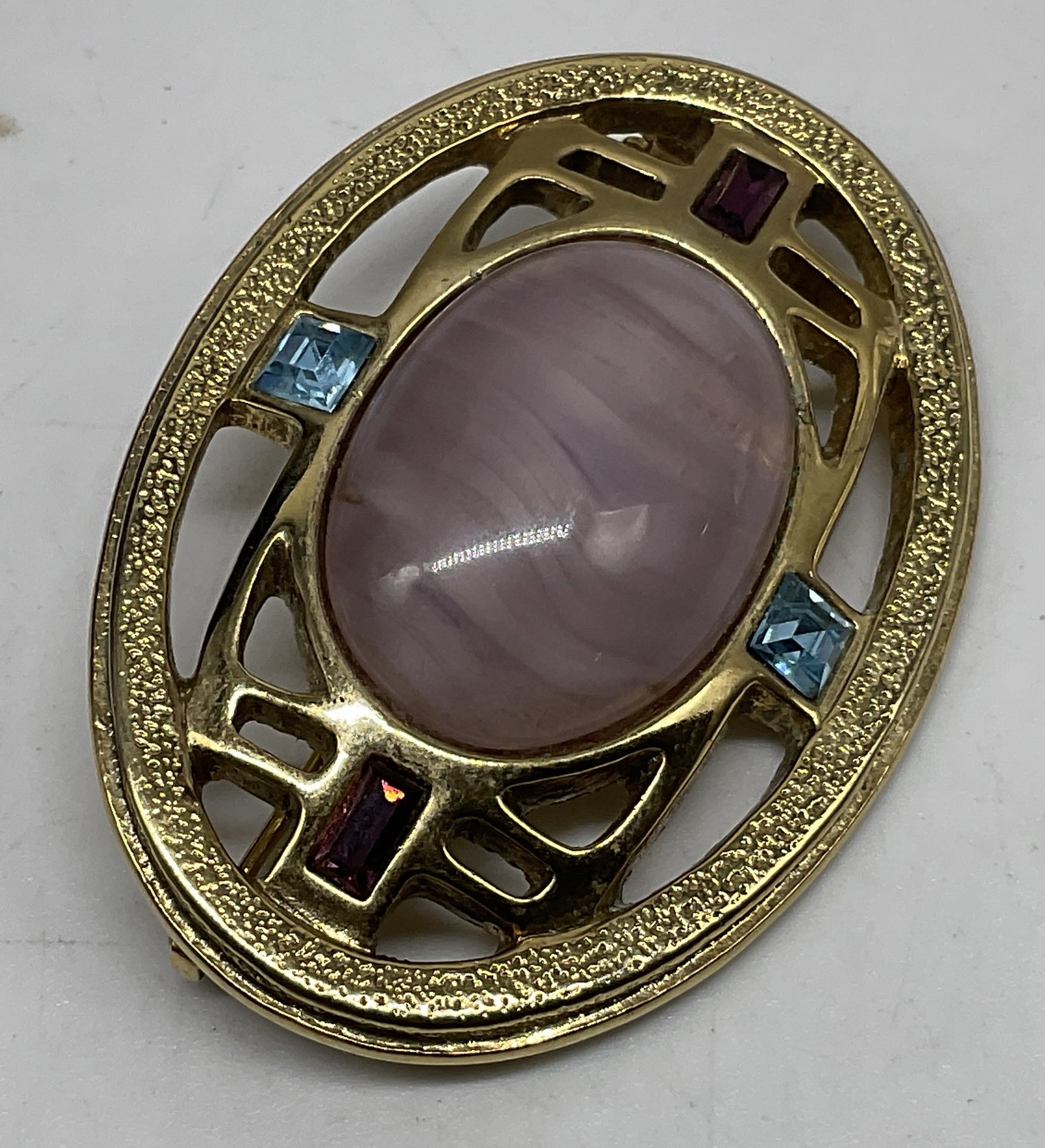 VTG C1928 Art Deco Pink Cabochon Brooch: Vintage Circa 1928 Art Deco Gold-Toned Filigree Brooch. Swirled pink glass cabochon center. Pink and blue rhinestone accents. Condition consistent with age and exposure. Measures approx 1.5 in Diam. v