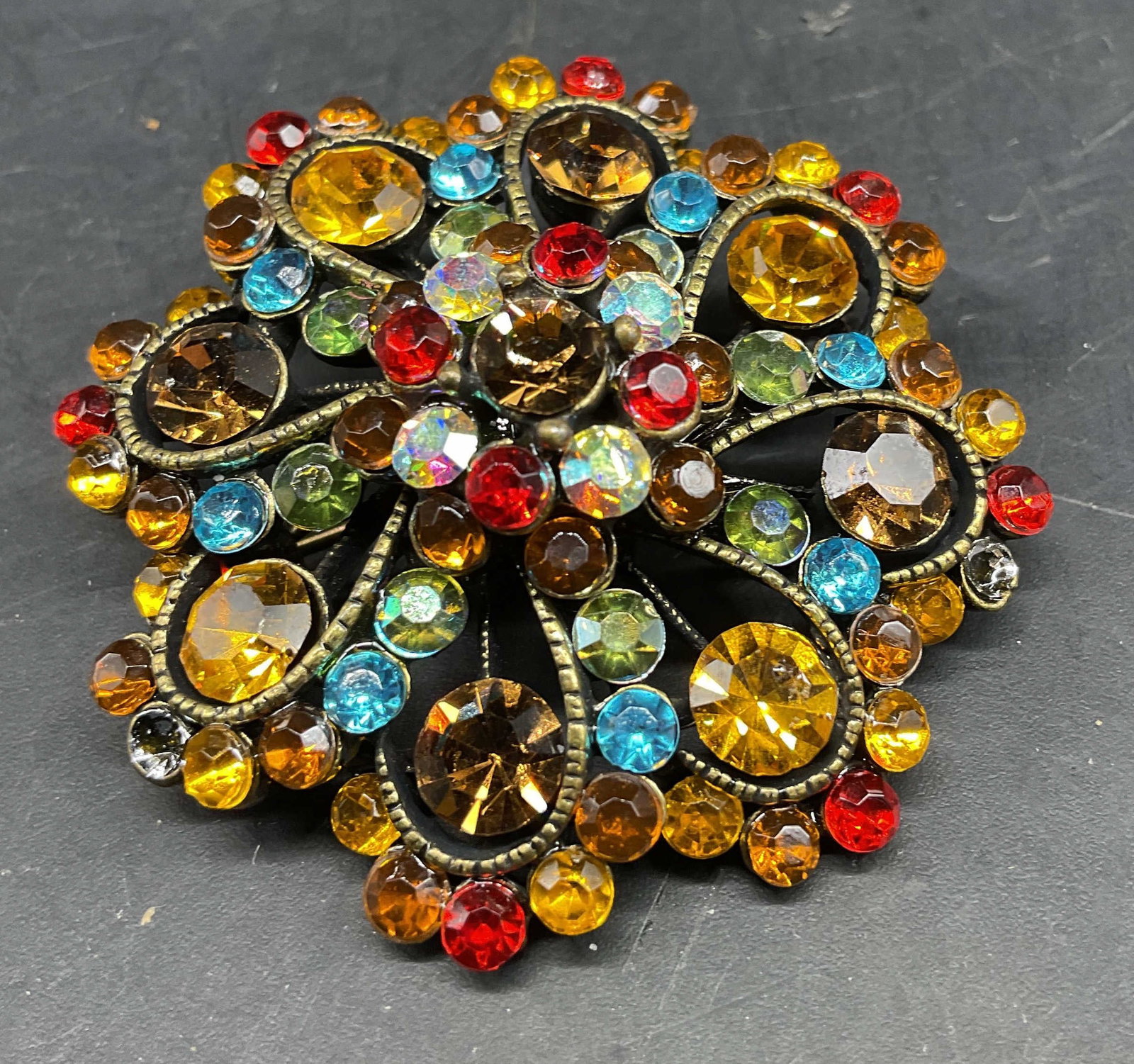 Vntg Multicolored Crystal Cluster Brooch: Vintage multi-colored rhinestone and crystal cluster brooch featuring vibrant amber, red and blue stones set in a gold tone filigree frame, American mid century costume jewelry, circa 1950s-1960s, sli