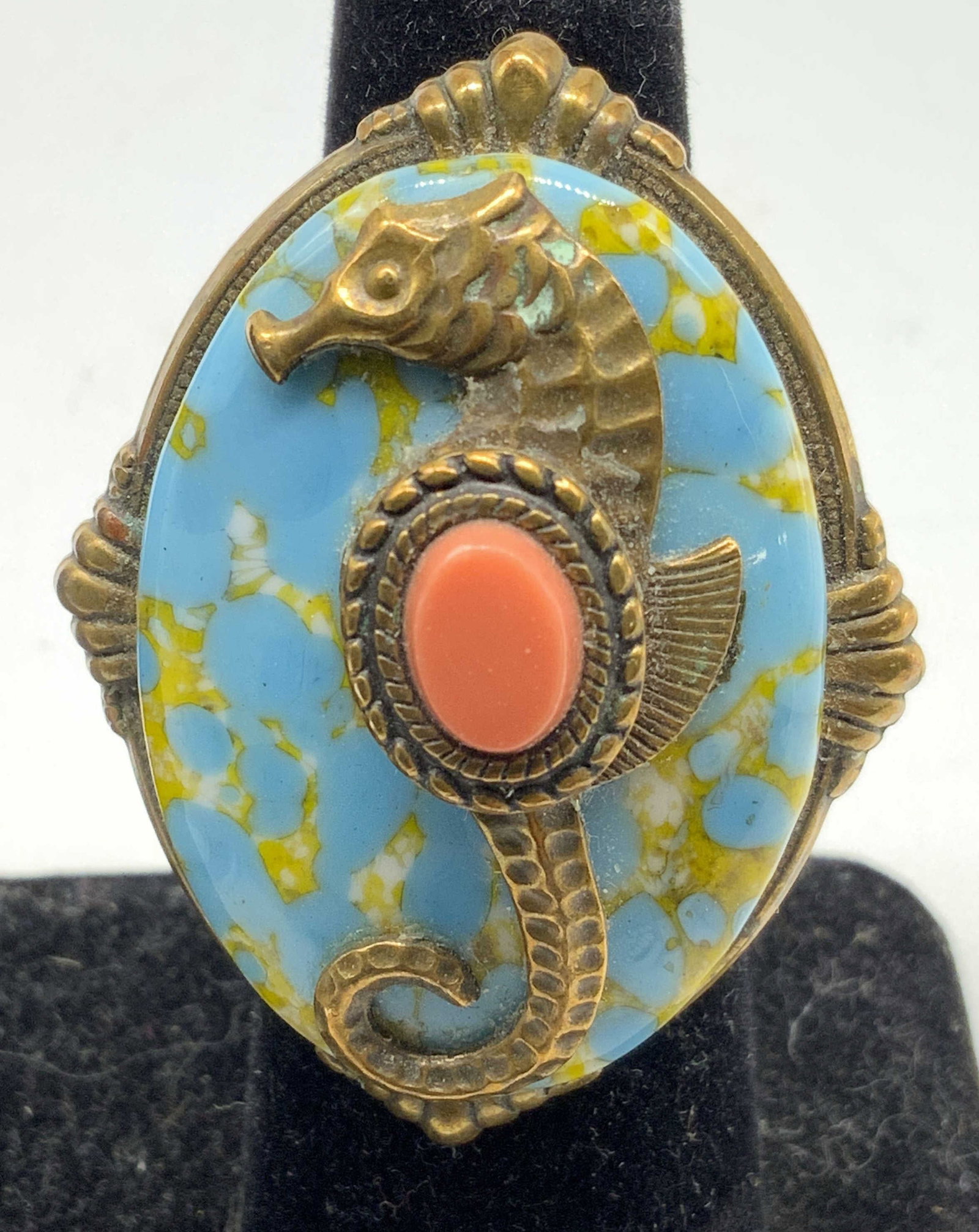 Vintage Sea Horse Statement Ring Jewelry: Vintage Statement ring features an ornate brass setting with a vibrant turquoise and yellow marbled stone backdrop, centered with a detailed brass seahorse holding a coral tone Cabochon belly! Oval me