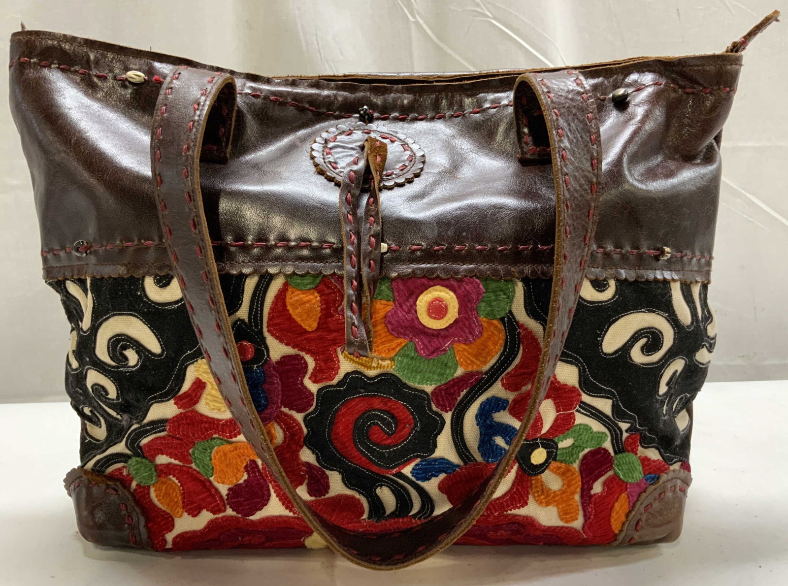 j. P. And Mattie Artisan Tote Leather Embroidery: J. P. And Mattie Collection artisan tote bag featuring dark brown leather panels paired with vibrant hand sewn floral textile applique has two handles each handle measures 12 inches ht, bag body
