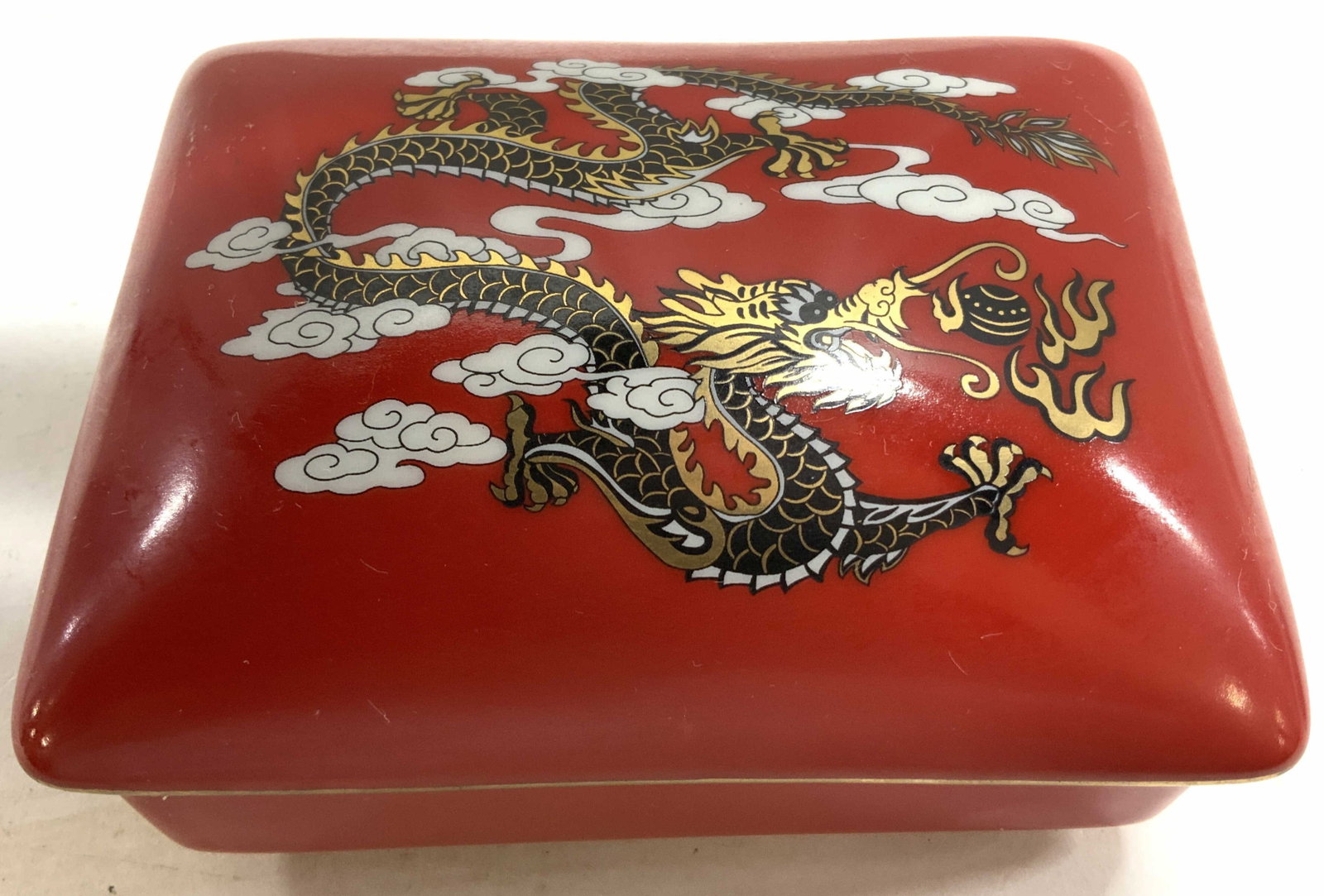 Red Dragon Porcelain Ceramic Lidded Box, Gumps: Signed underside for Gumps, luxury San Francisco Department Store specializing in Asian decorative arts, red porcelain ceramic lidded box, featuring hand painted black and gold toned dragon and clouds
