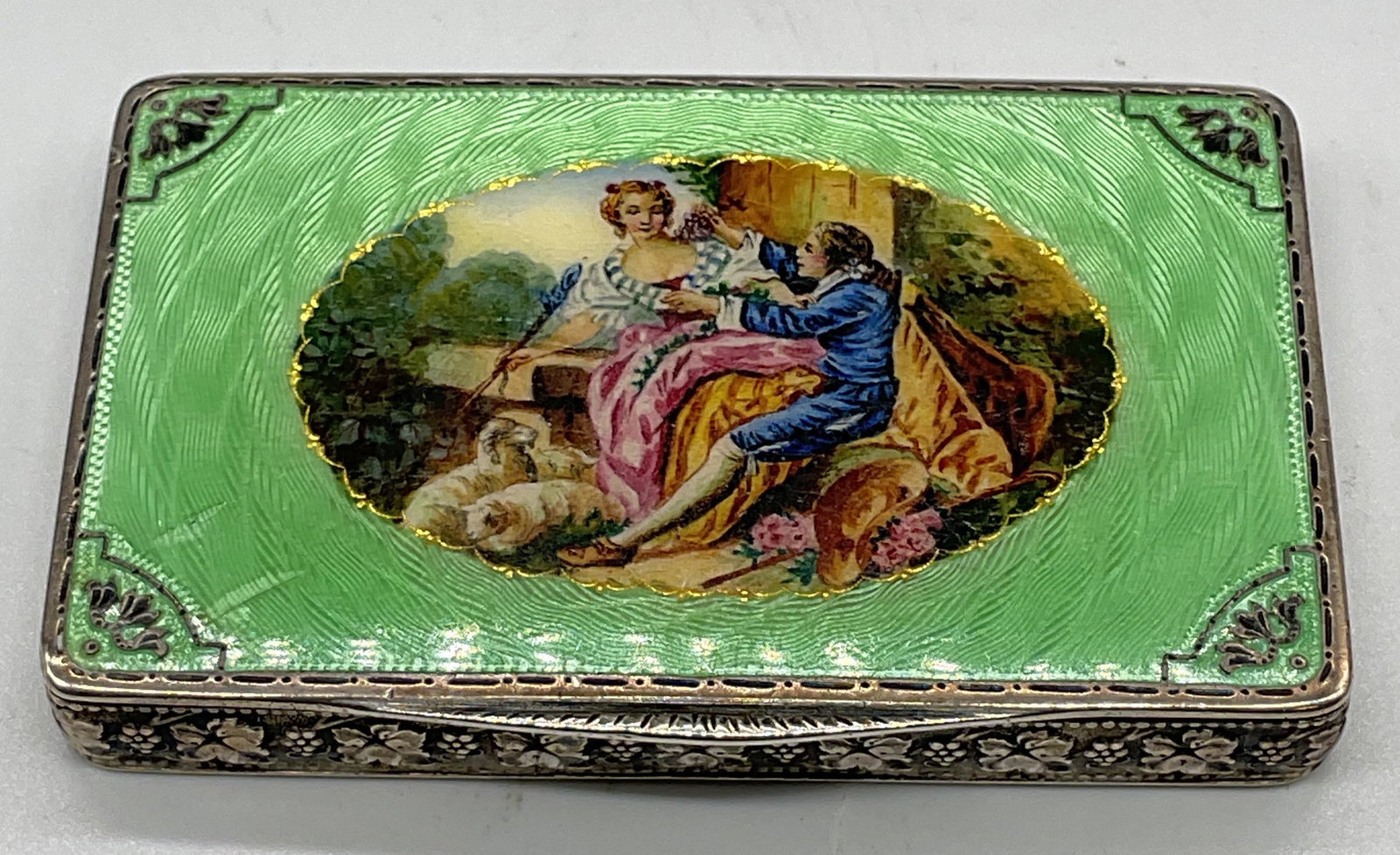 Antique Sterling Silver Guilloche Box Austria: Antique sterling silver guilloche enameled box. Raised floral panels with green guilloche enamel and central courting couple scene. Interior mirror. Marked illegibly on interior and numbered 979. Mark