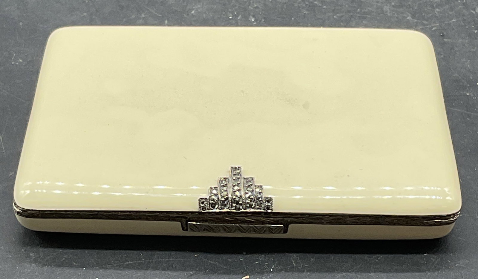 Art Deco Sterling Silver White Enamel Box: Vintage, possibly antique, art deco sterling silver box. White enameled case with wheat pattern frame. Clasp setting with geometric marcasite decoration. Gold plated interior. Measures approx. 3.35 x 