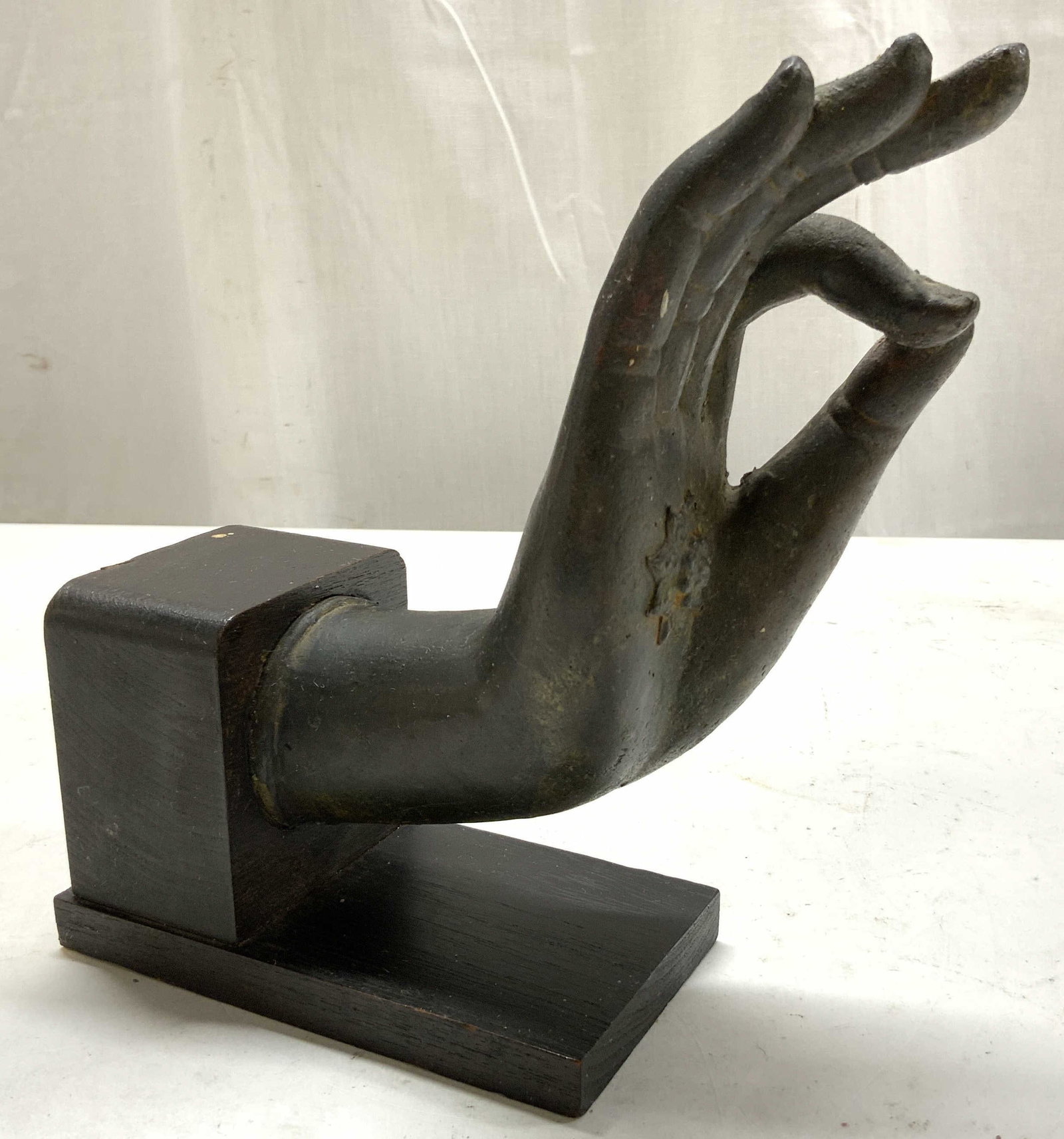 Patinaed Bronze Buddhas Hand Sculpture: Cast Bronze metal buddhas hand sculpture mounted on a wood display base, molded in the traditional Vitarka Mudra gesture of discussion and teachings, design features elongated fingers with a stylized 