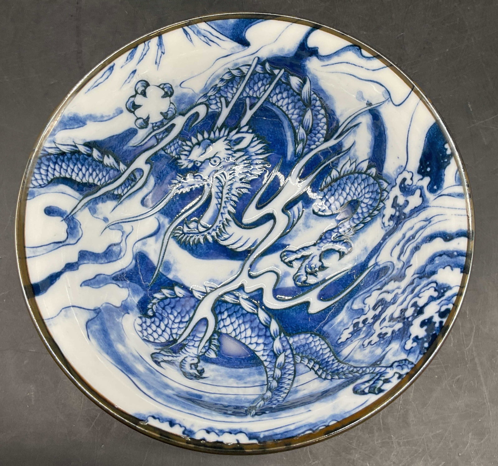 Sgnd Dragon Design Blue White Porcelain Bowl: Signed on underside with Asian characters, marked made in Japan, blue and white porcelain bowl with dragon design and silver toned rim, Asian decorative arts, measures ht app 2.75 inches, diameter