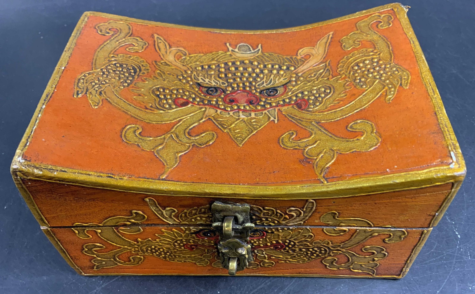 Hand Painted Orange Gold Dragon Box: Traditional hand painted Himalayan Tibetan Style Wood storage box featuring a vibrant orange finish and ornate dragon motifs, raised golden detailing gold toned metal clasp and concave curved lid deta