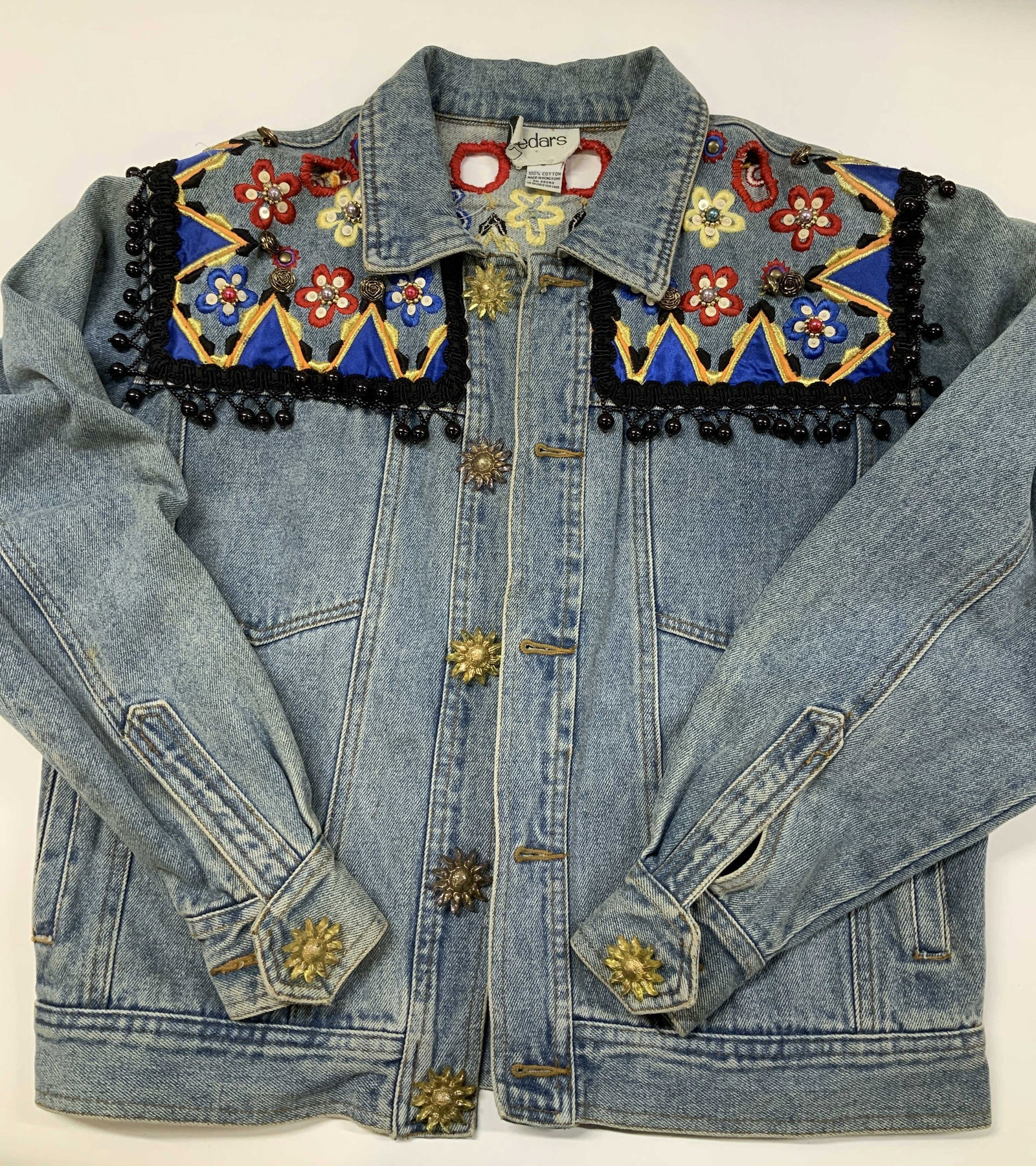 Vntg Cedars embellished denim jacket: Vintage Cedars embellished denim jacket. Made from 100% cotton. The upper yoke features a vibrant multi colored triangle pattern outlined in yellow piping contrasting against cobalt blue panels. The