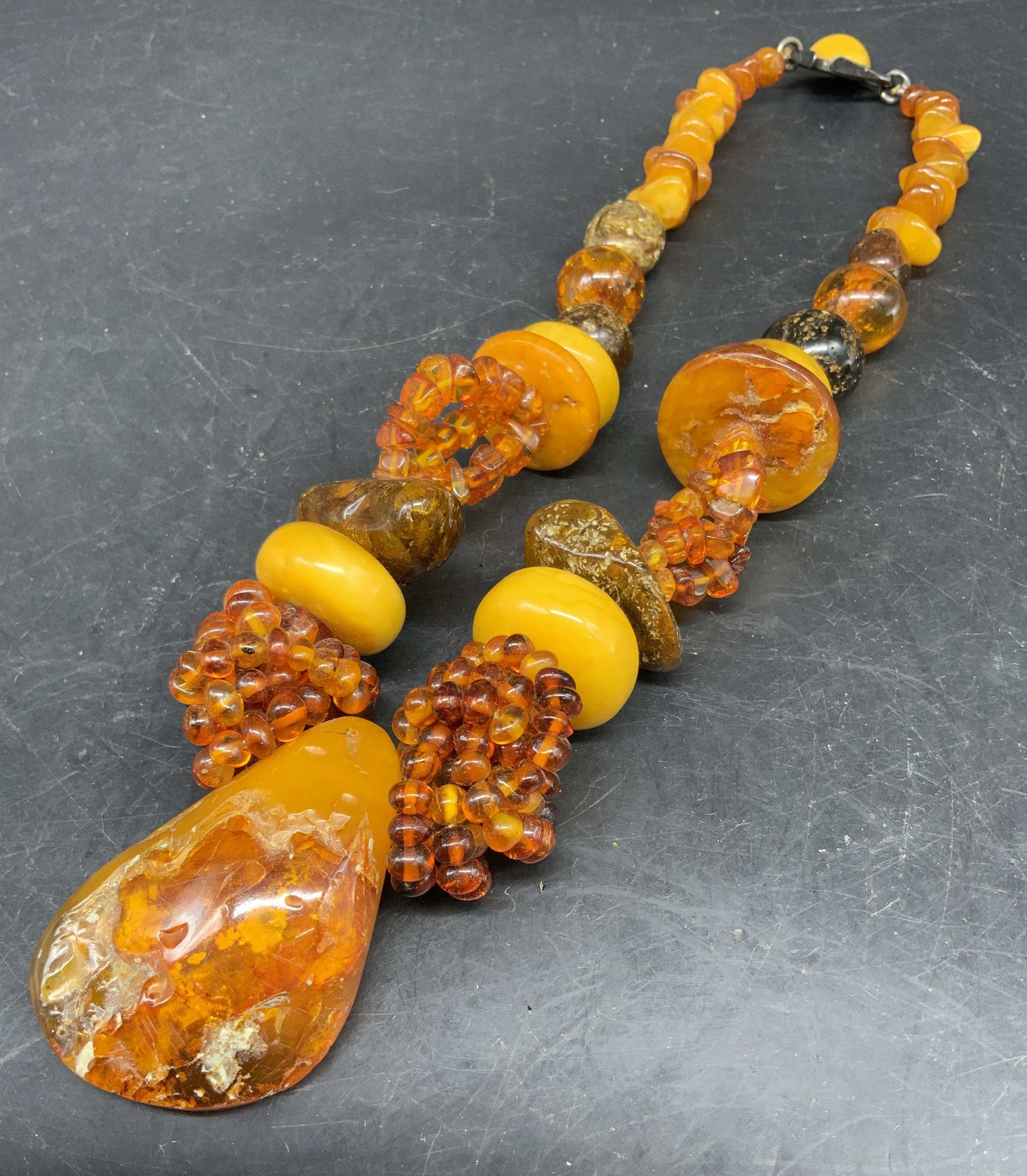 Antq Natural Baltic Amber Statement Necklace: Vintage Baltic amber Statement necklace featuring mixed butterscotch and honey colored amber beads alongside a large teardrop pendant, silver horseshoe shaped clasp with butterscotch cabochon, promine