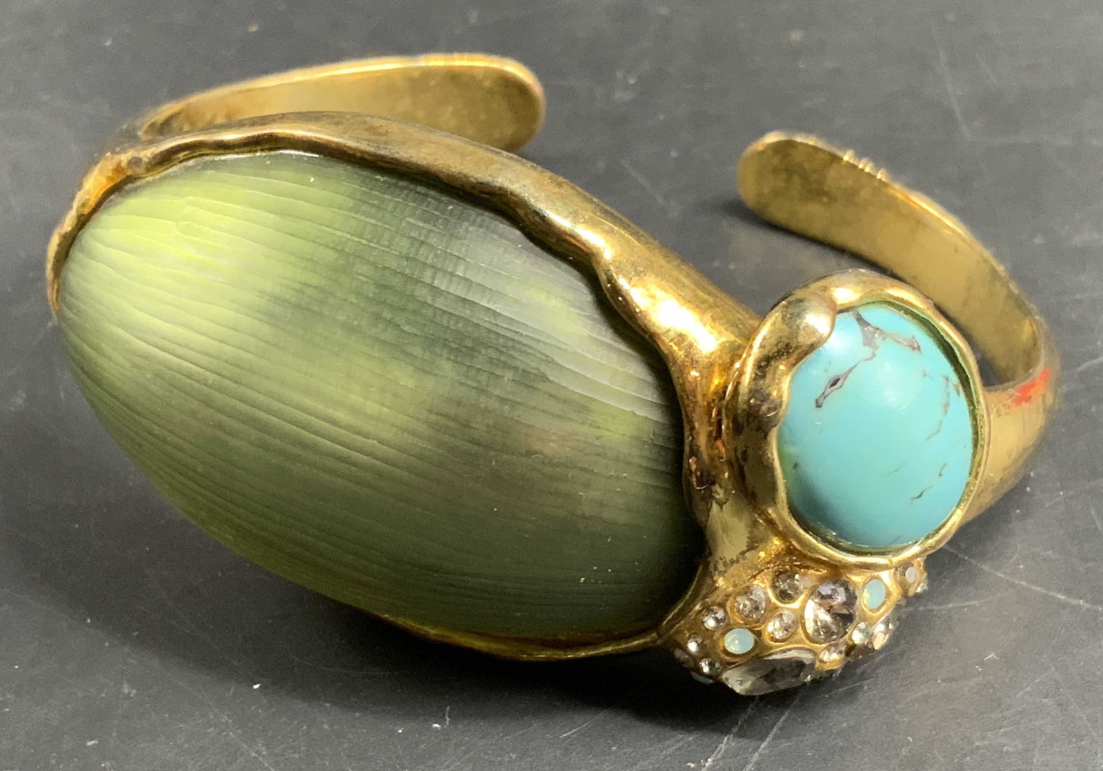 Alexis Bittar Crafted Stone Lucite Cuff Bracelet: Signed with initials A.B. inside of cuff, early Alexis Bittar hand crafted gold tone cuff bracelet, features a large 2 inch textured green lucite center a brushed gold tone cuff accented with