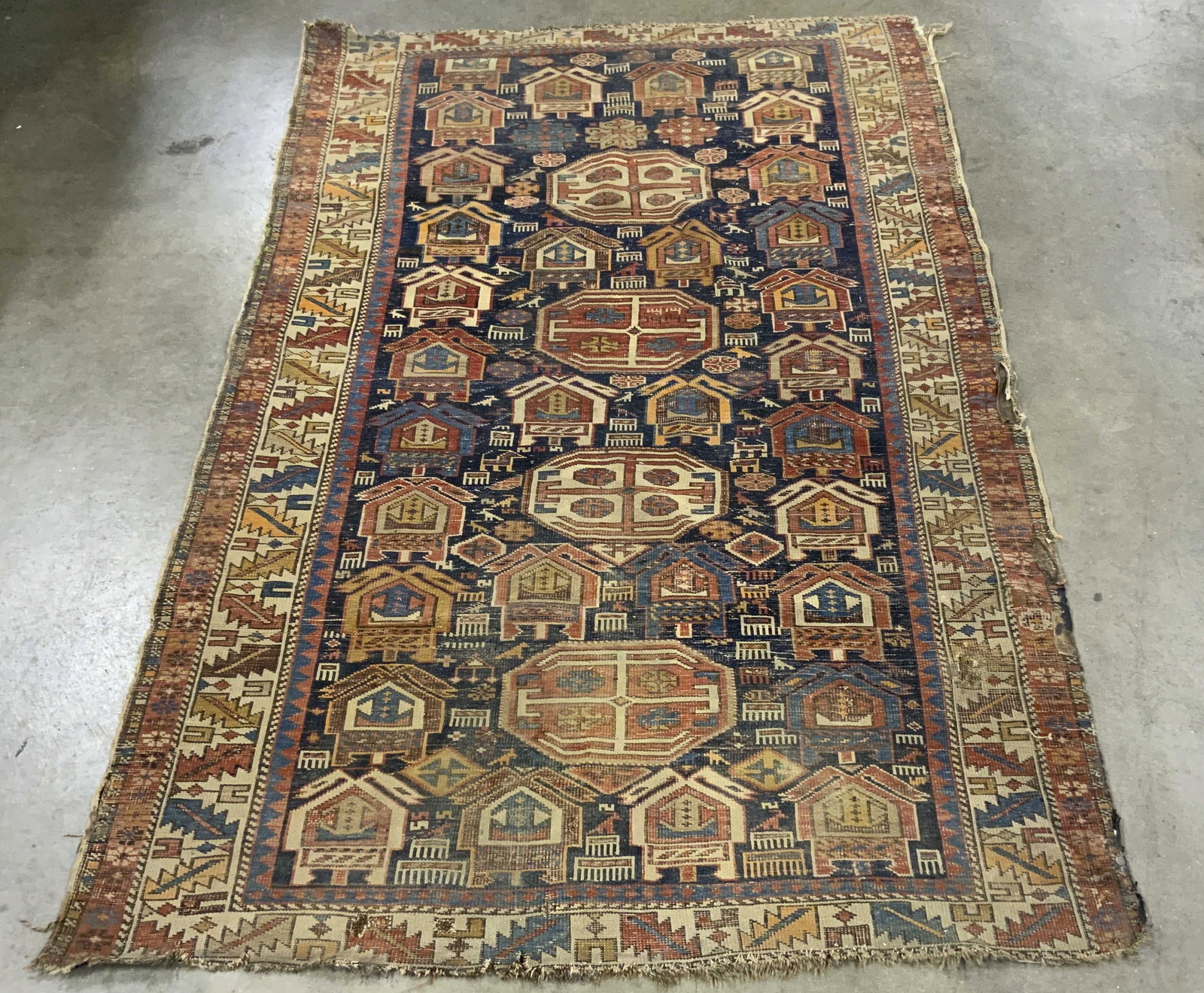 Traditional hand made wool tribal rug: 69 by 45 inches measurement of traditional hand made wool tribal rug, significant wear and color fading, features an intricate geometric pattern with repeated architectural motifs on a dark blue field