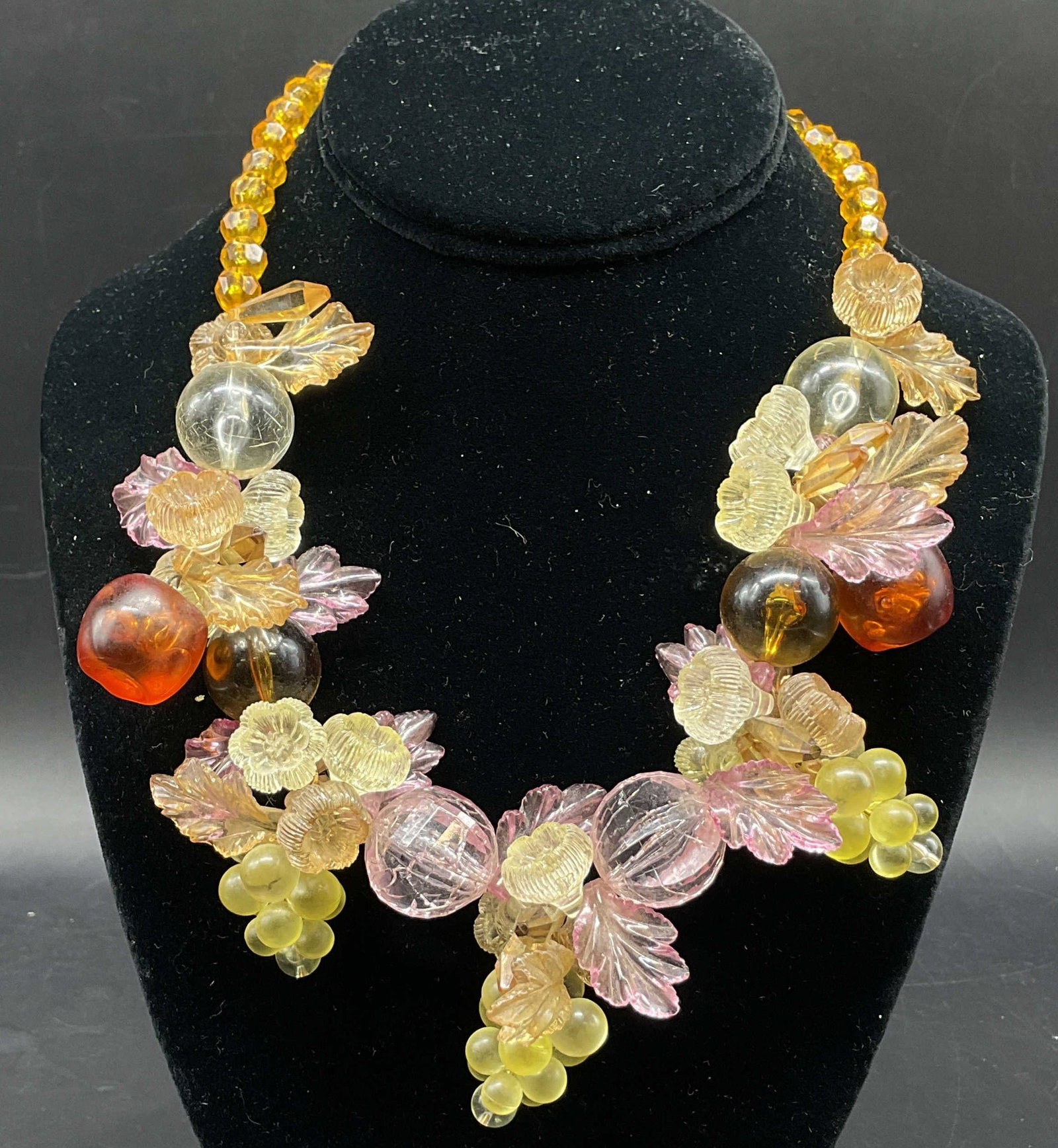 Vintage Lucite Fruit Salad Statement Necklace: Vintage lucite fruit salad statement necklace. Molded fruit clusters, including grapes and apples. Round beads with floral and leaf motifs. Orange bead accents. Varying colors. Measures approx 8