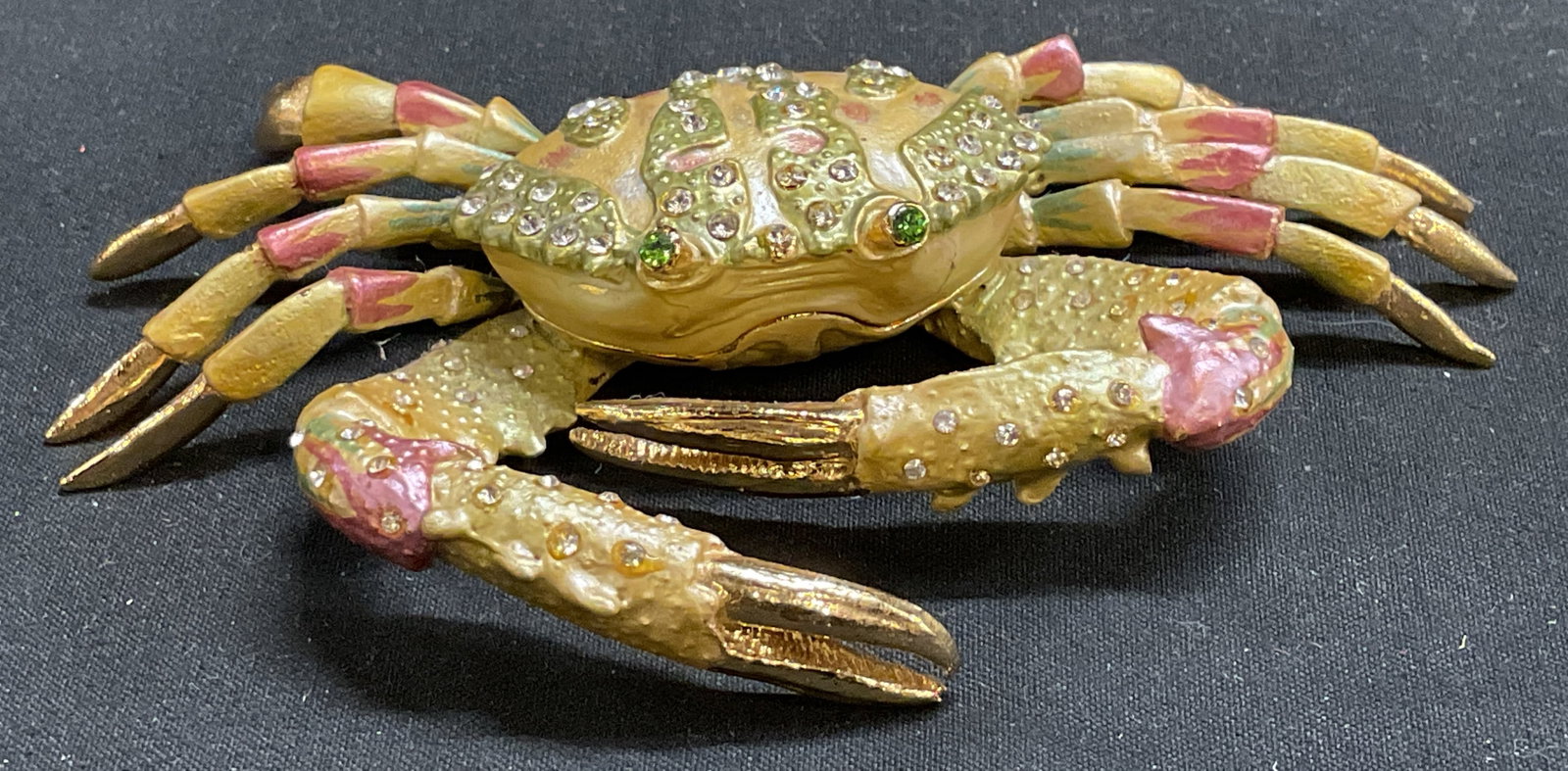 Bejeweled Enameled Crab Trinket Box: Gold-Toned Crab Trinket Box. Yellow, green, and pink enamel design. white rhinestone accents. Green rhinestone eyes. Magnetic clasp. Some coating loss. Measures app 1in H x 4.5in L. gold-toned,